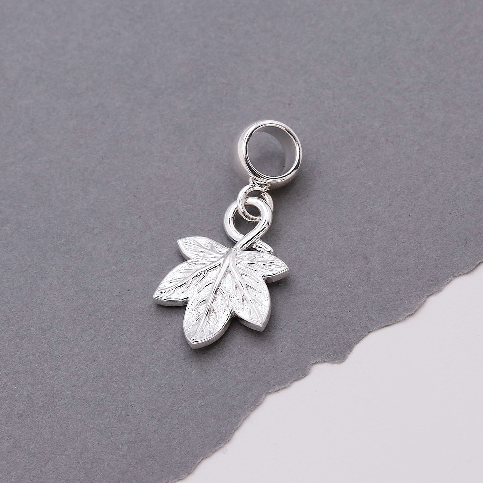 Silver leaf charm on a gray background