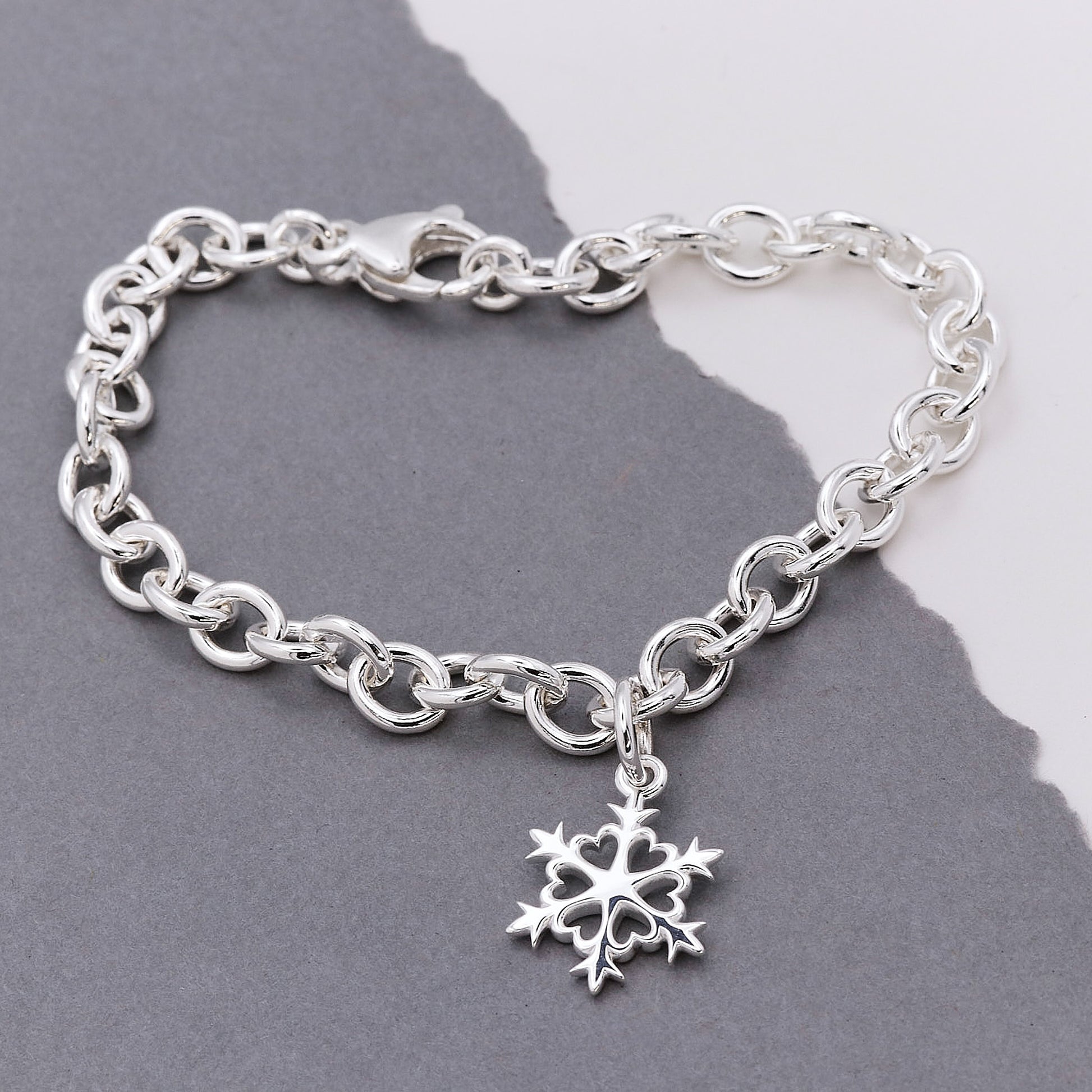 Silver chain bracelet with a snowflake charm on a gray background