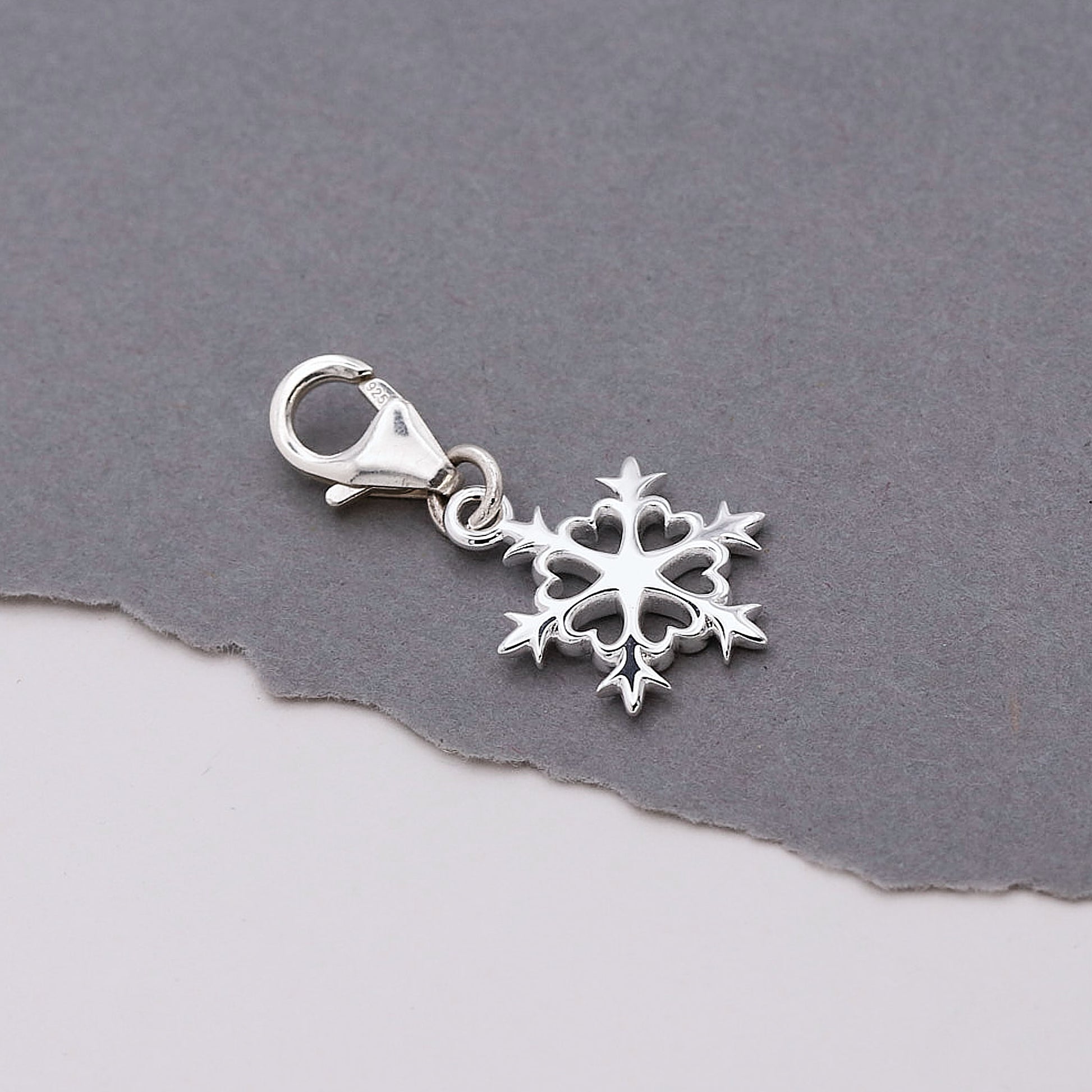 Silver snowflake charm on a gray background