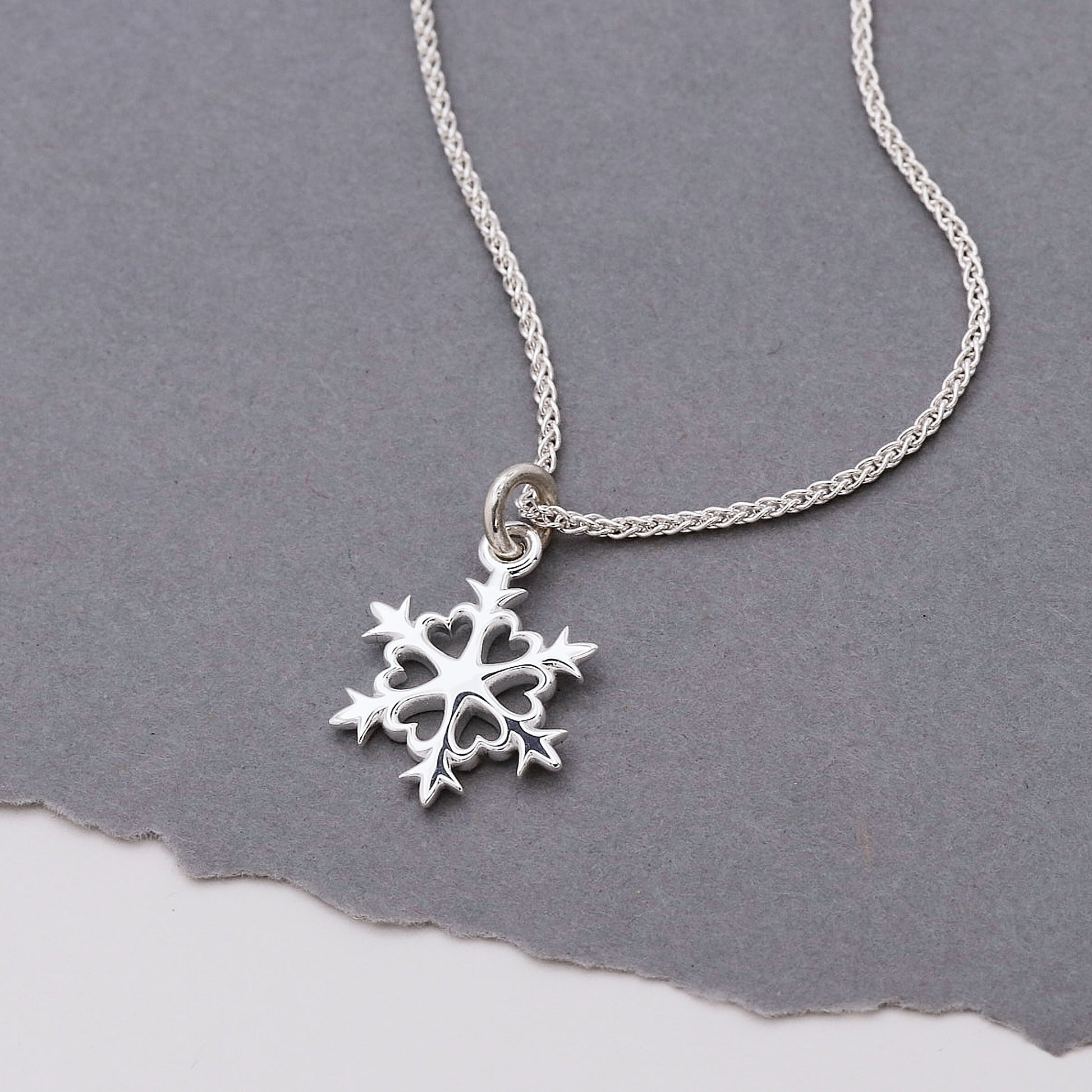 Silver snowflake pendant necklace on a gray background