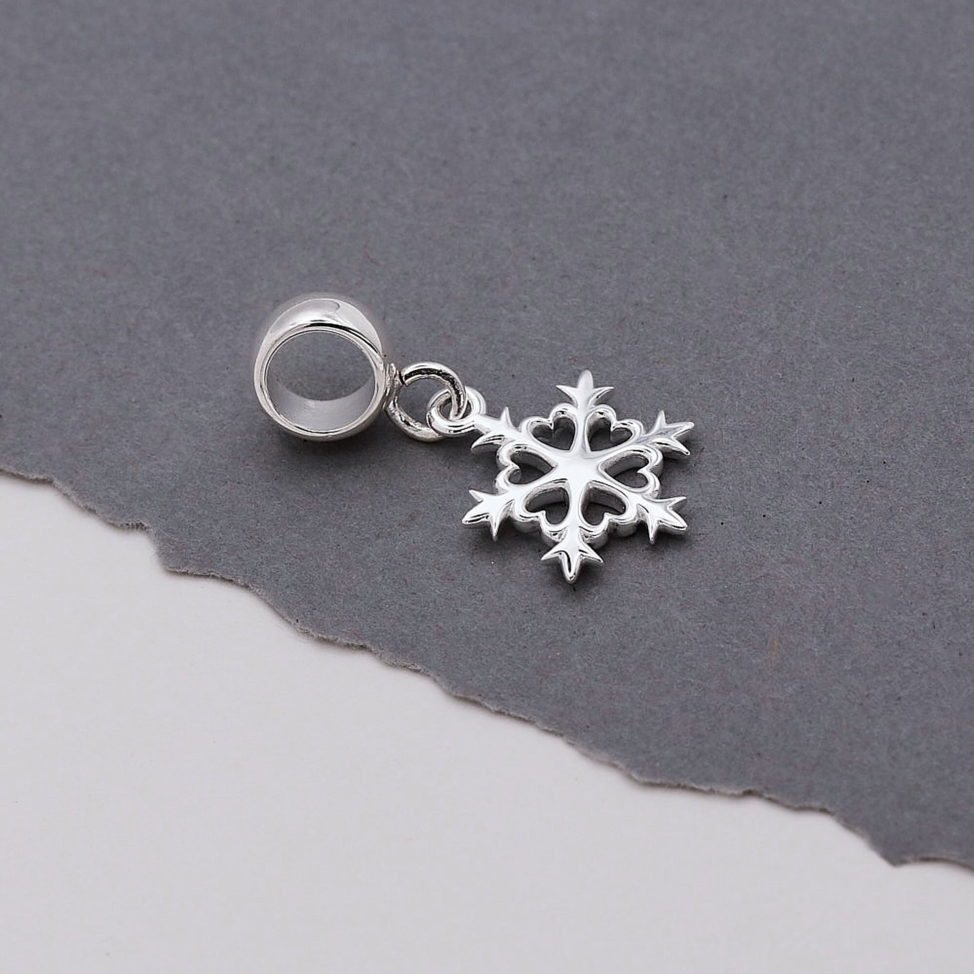 Silver snowflake charm on a gray background