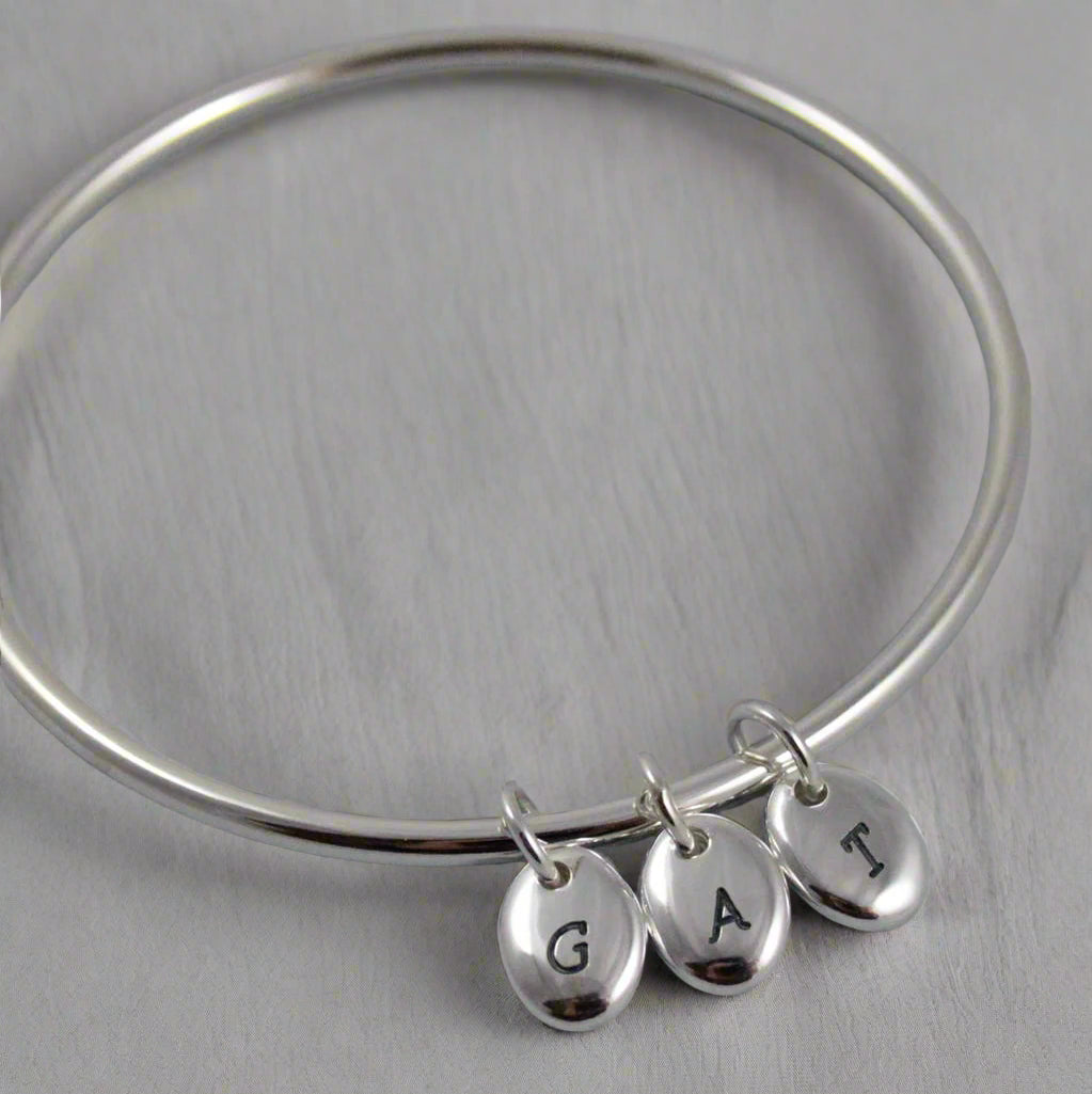 silver bangle with three personalised silver pebble charms for mothers day gift