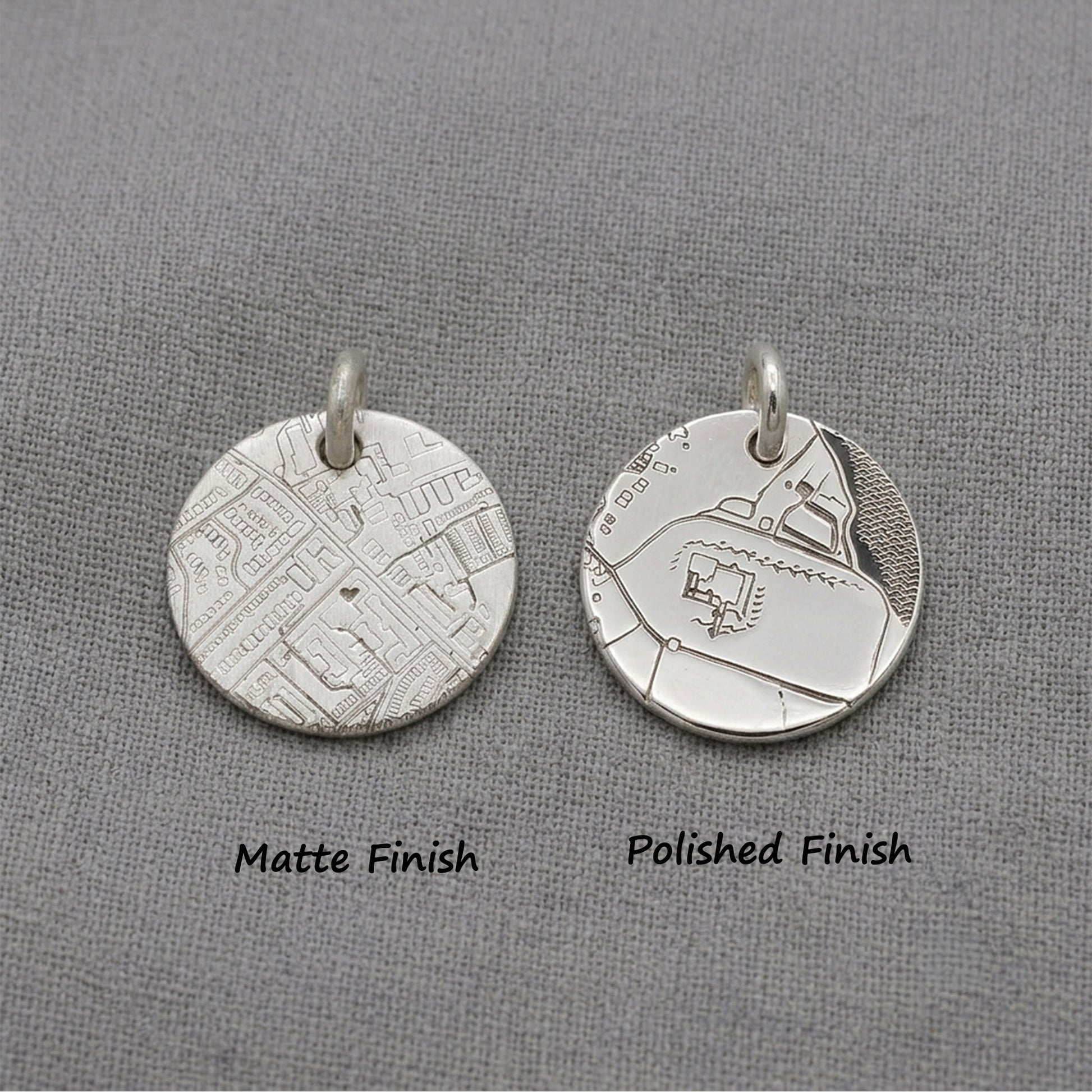 Two silver pendants, one matte and one polished, on a gray background.