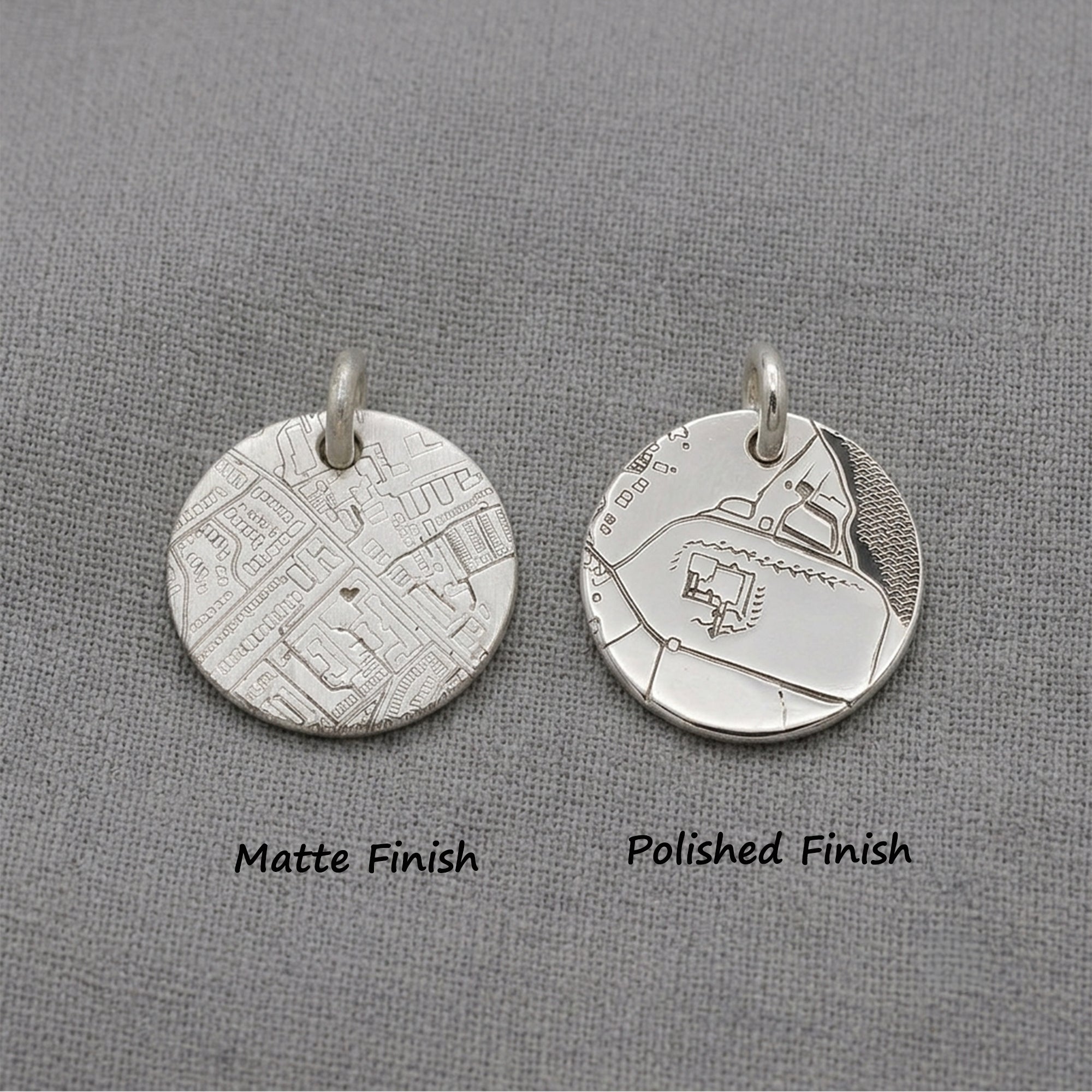 Two silver pendants, one matte and one polished, on a gray background.