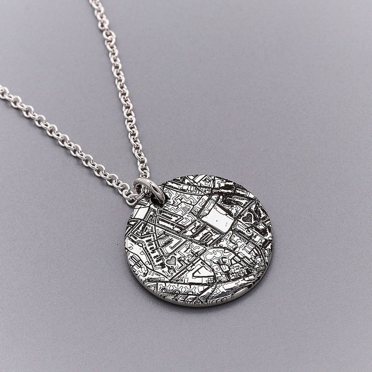 Silver necklace with a round pendant on a gray background