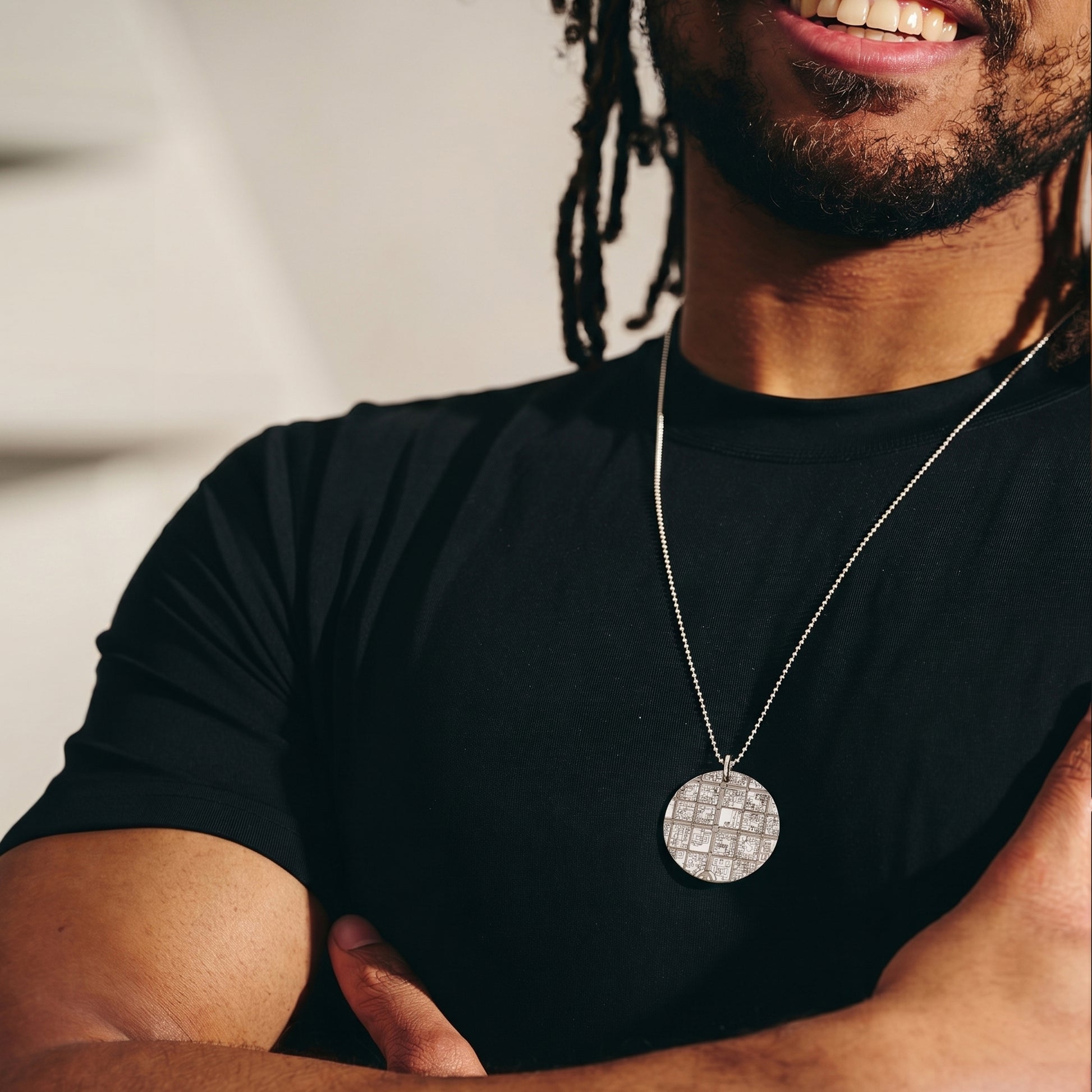 man wearing necklace with map design and black t-shirt