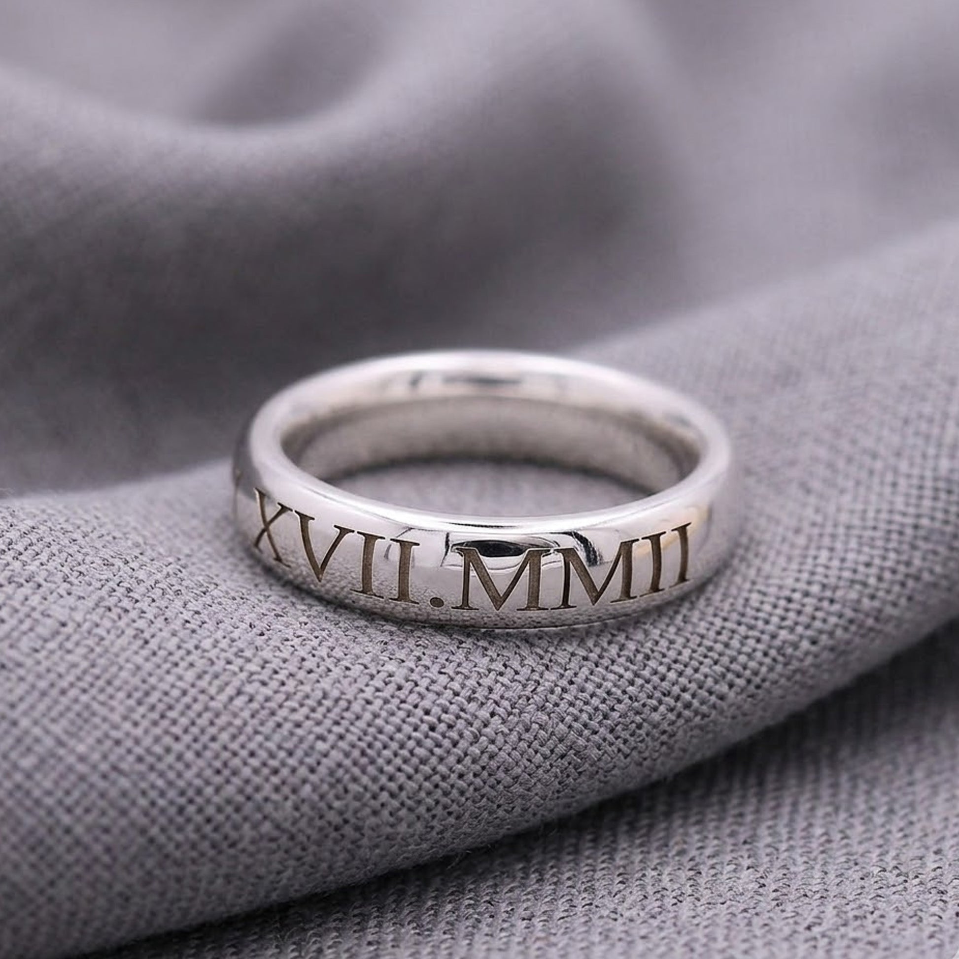 Silver ring with Roman numerals on a gray fabric background