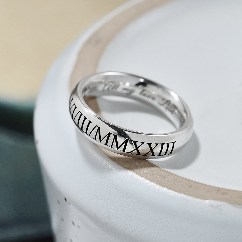 Silver ring with Roman numeral engraving on a white surface