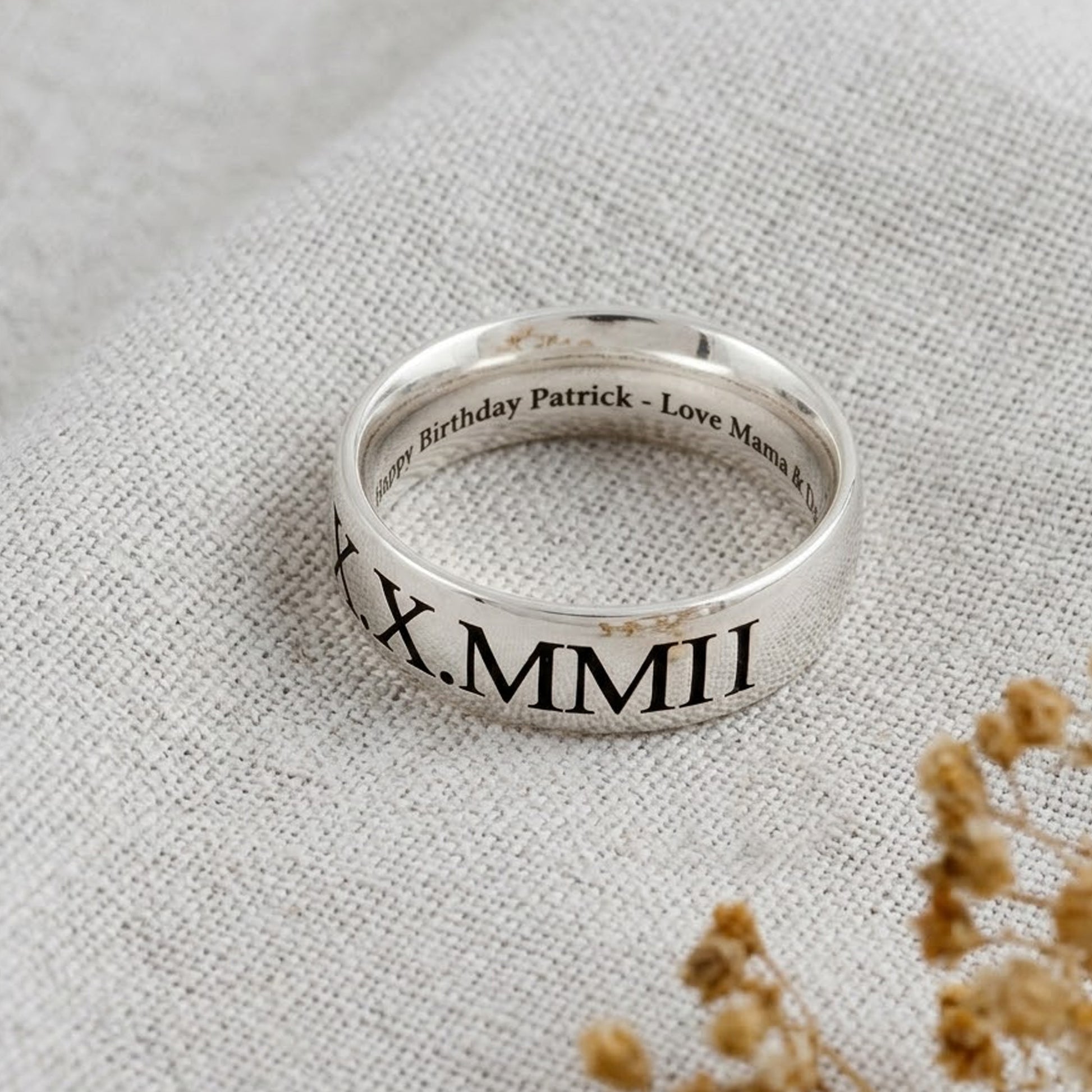 Silver ring with engraved text on a textured fabric background