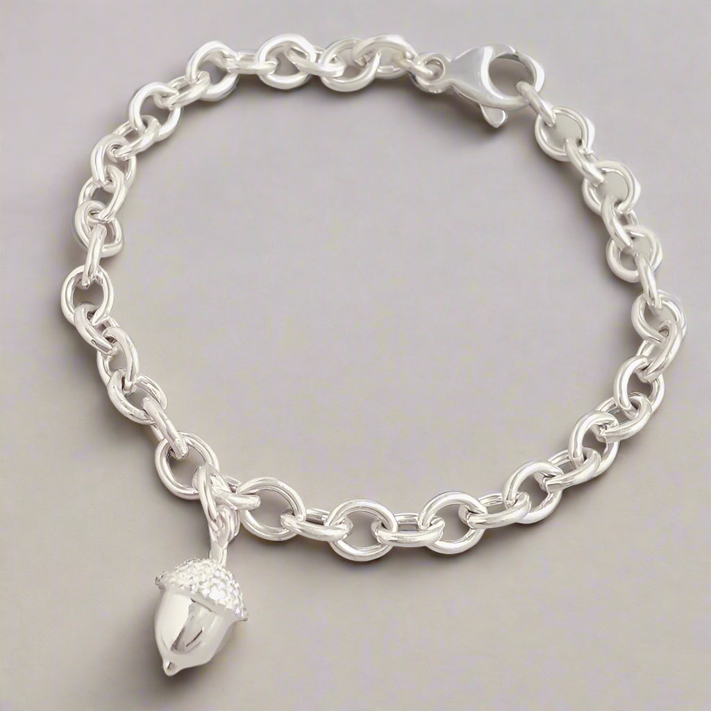 Silver chain bracelet with an acorn charm on a light gray background