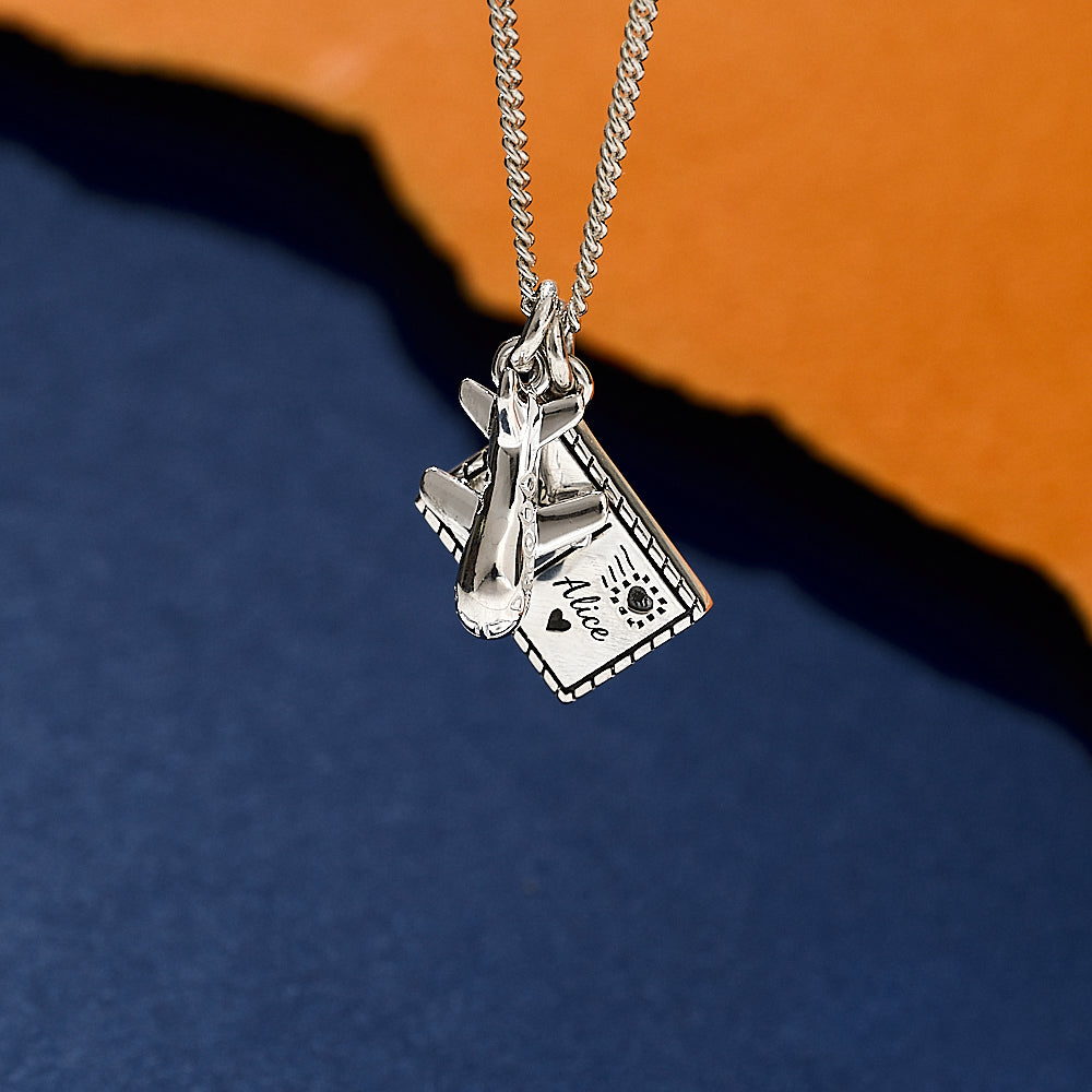 Silver necklace aeroplane and postcard with a pendant on a blue and orange gradient background