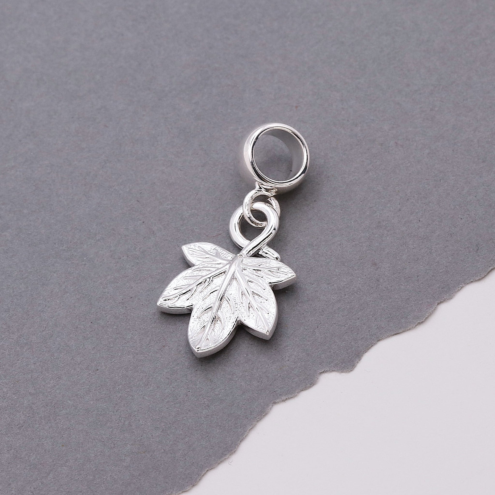Silver leaf charm on a gray background