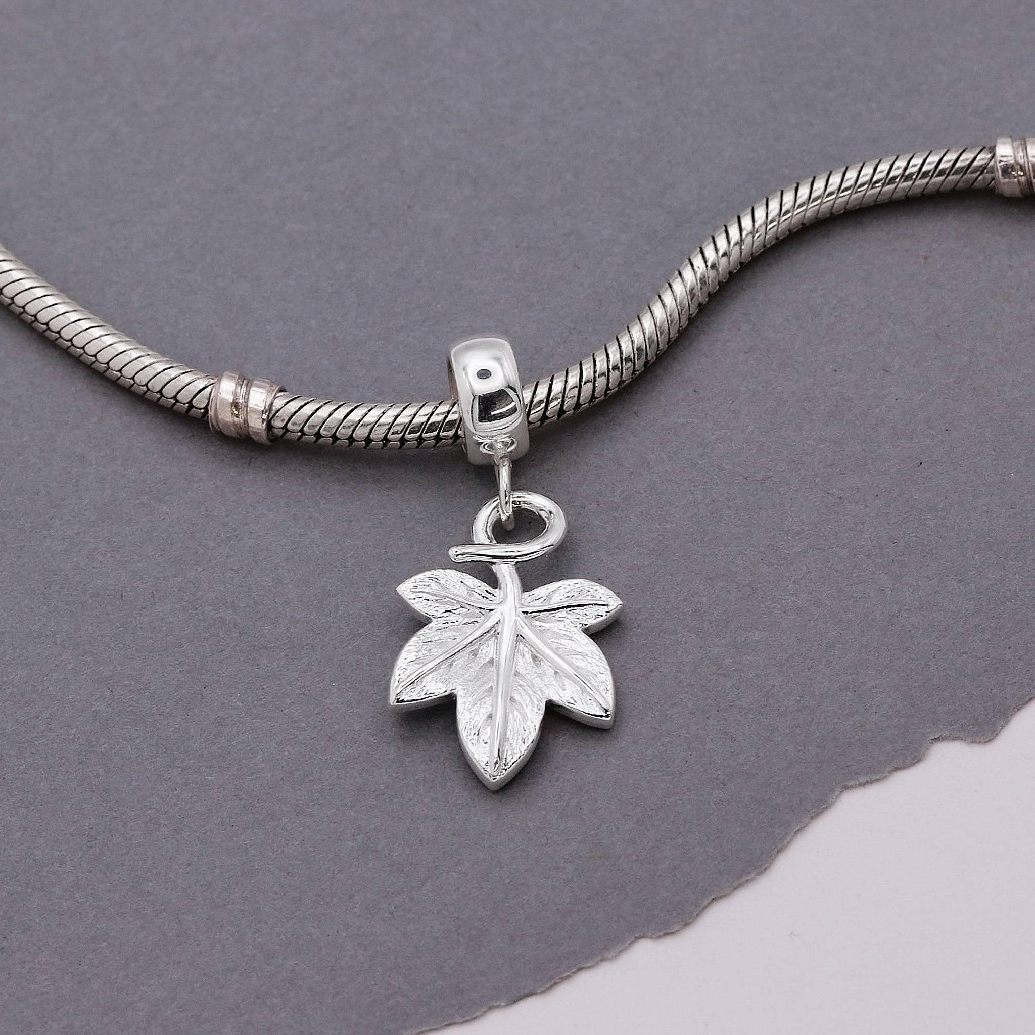 Silver bracelet with a leaf-shaped charm on a gray background