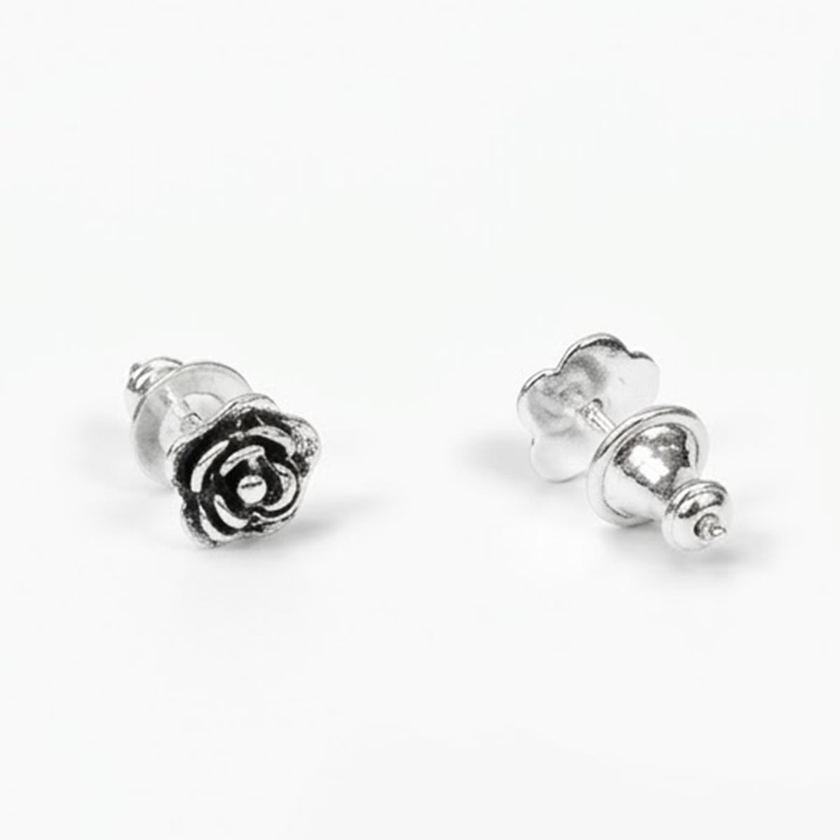 A pair of silver rose stud earrings, one shown from the front displaying the rose detail and the other from the side showing the post and butterfly back, on a clean white background.