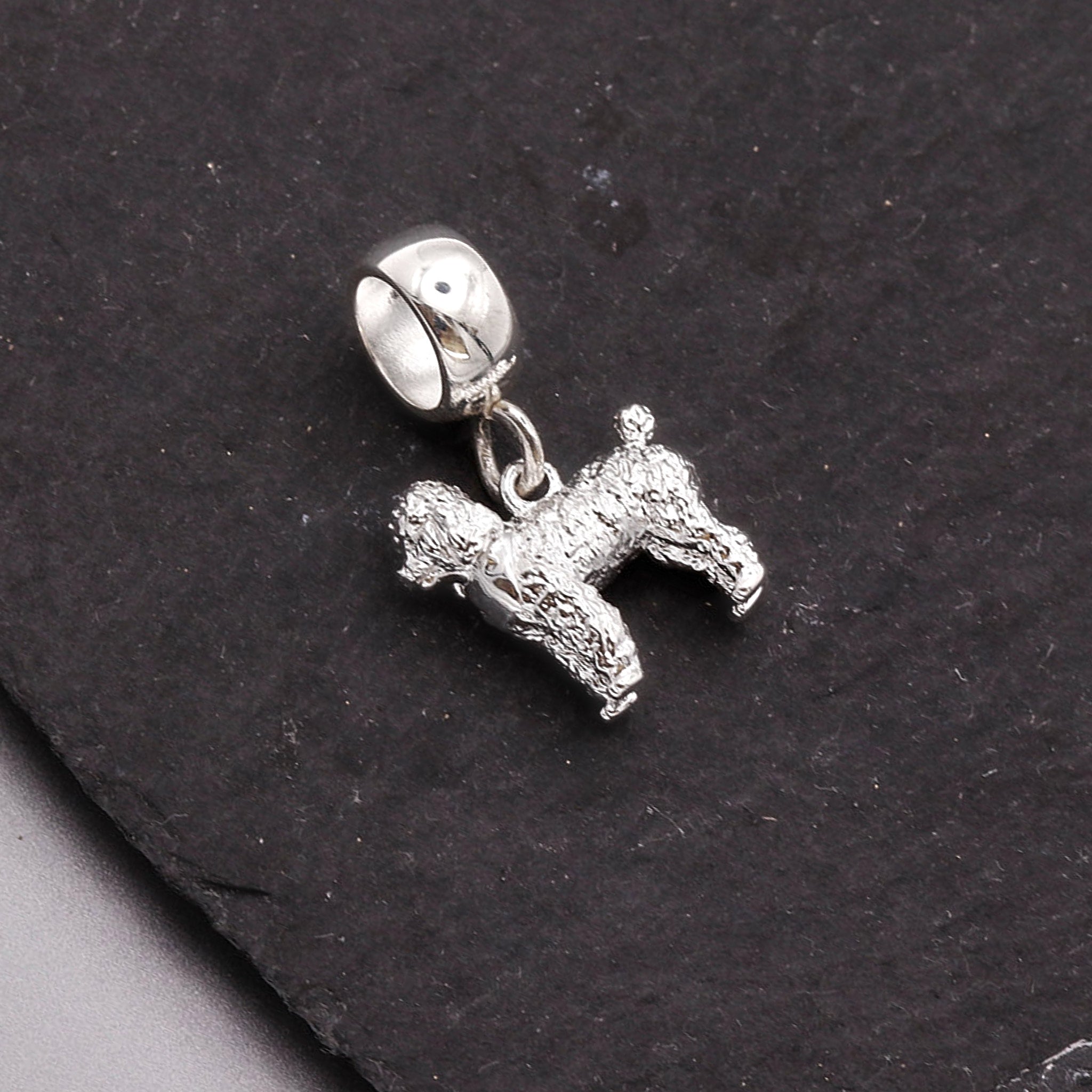 Silver dog charm on a black stone background