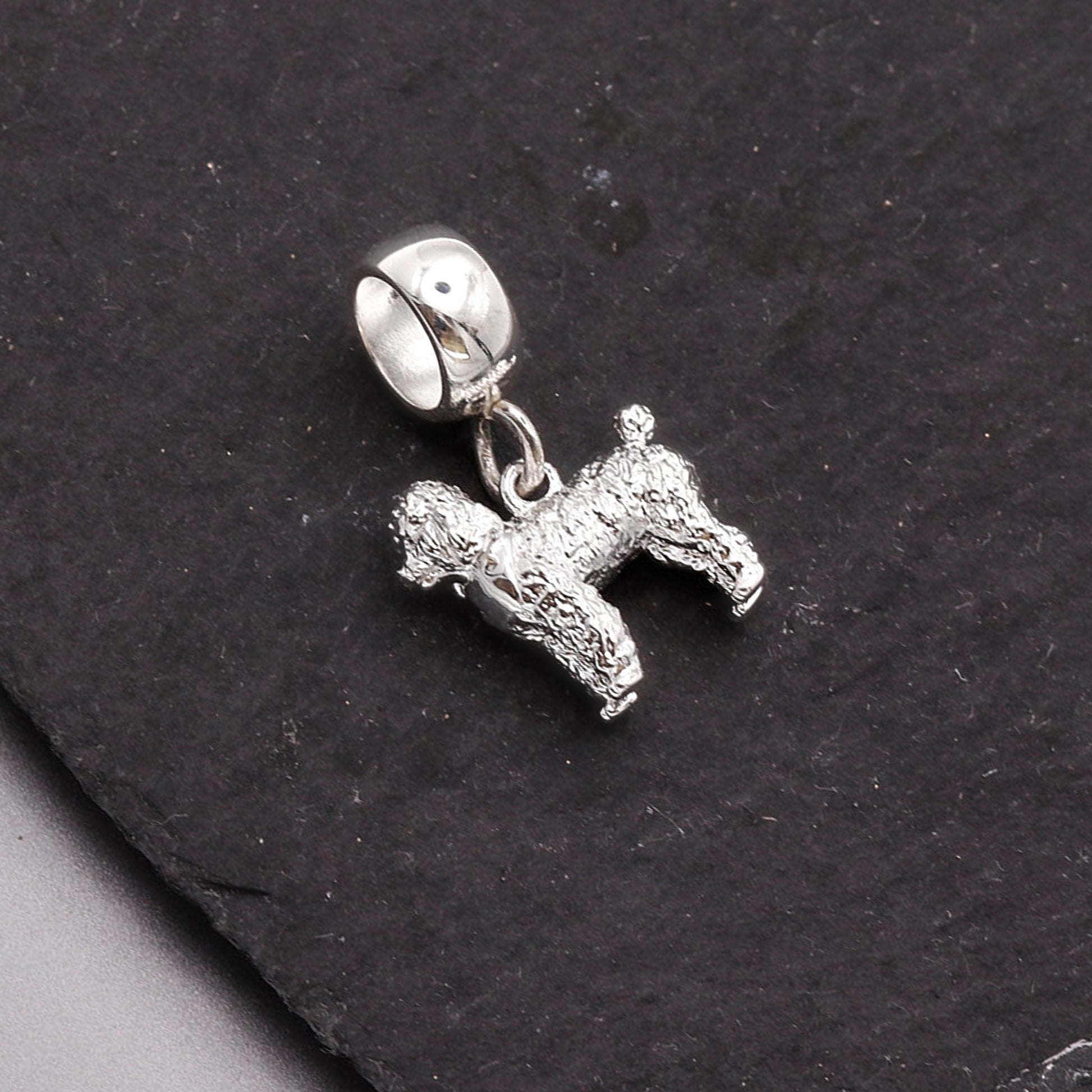 Silver dog charm on a black stone background
