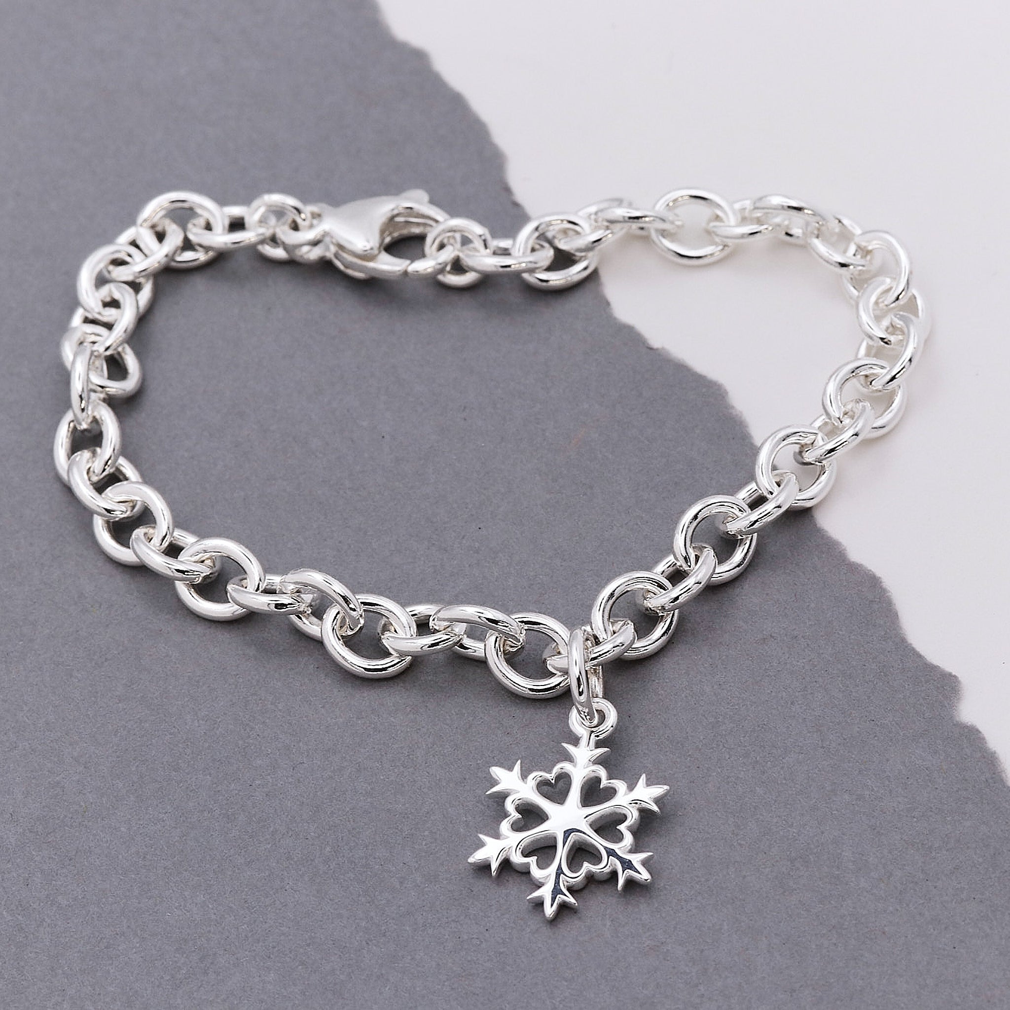 Silver chain bracelet with a snowflake charm on a gray background
