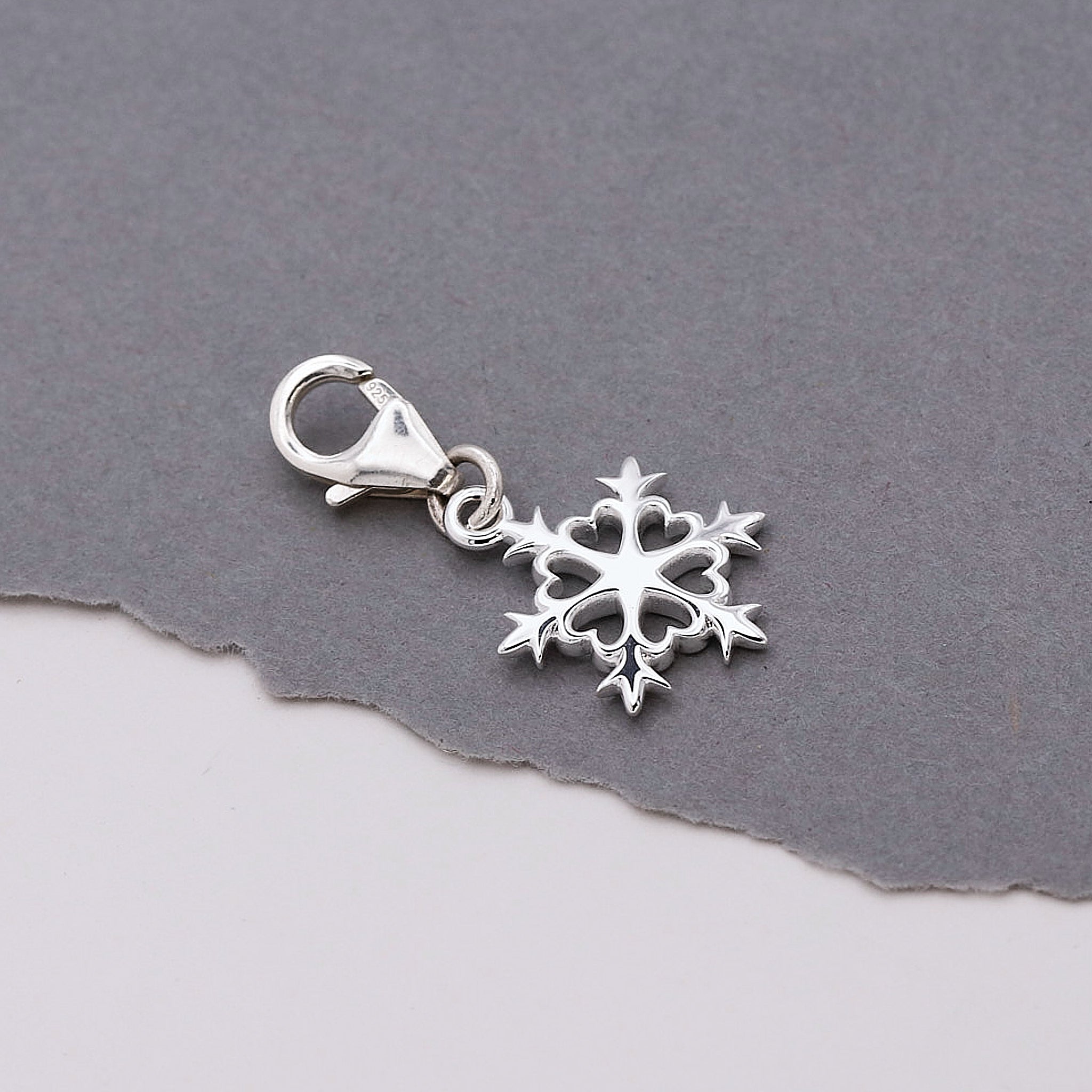 Silver snowflake charm on a gray background