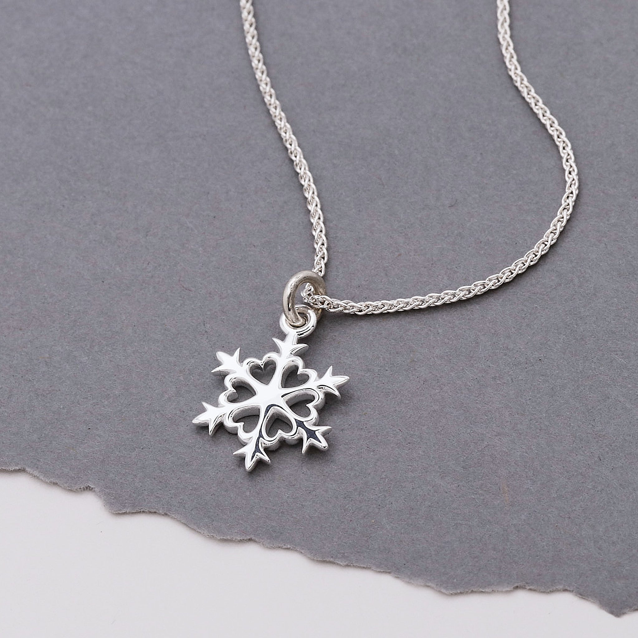 Silver snowflake pendant necklace on a gray background