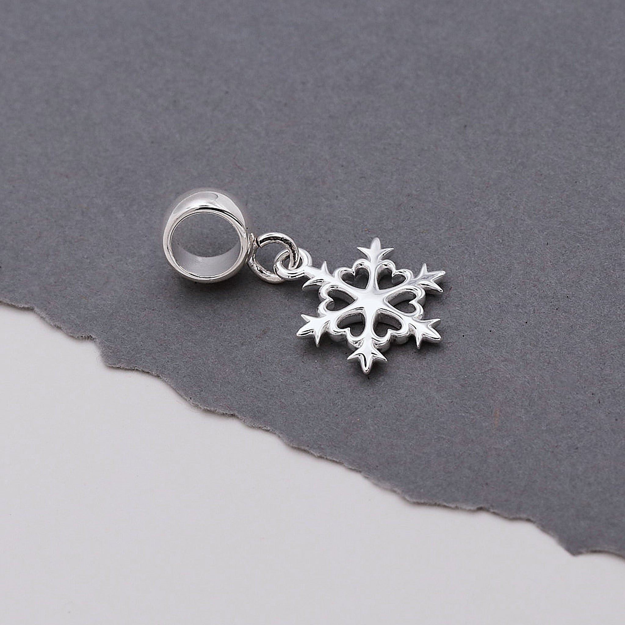 Silver snowflake charm on a gray background