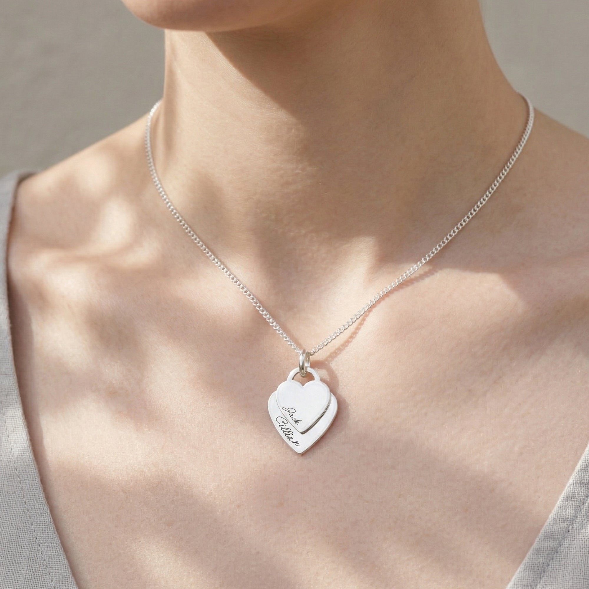 Silver necklace with a heart-shaped pendant on a person's neck
