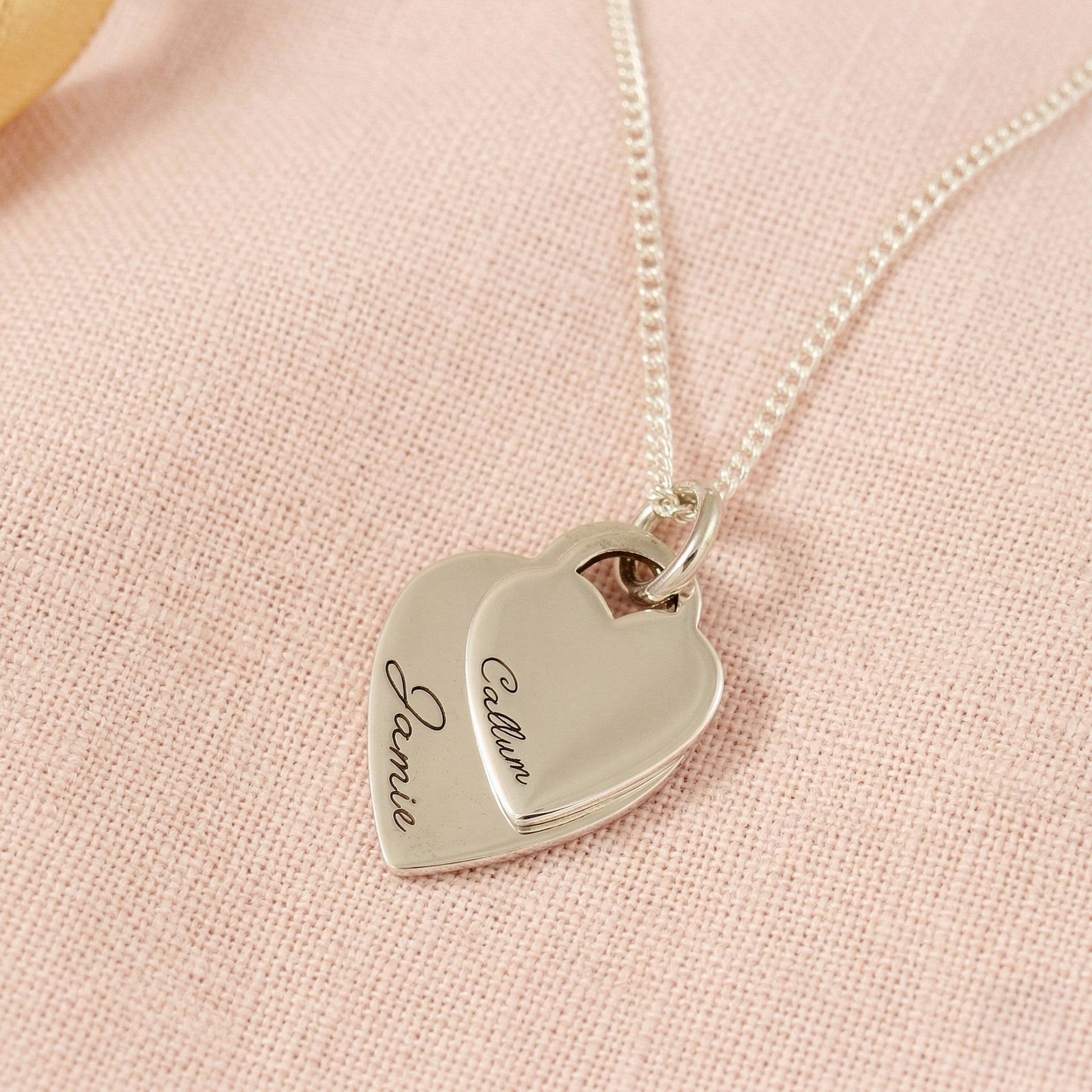 Silver heart-shaped pendant necklace on a pink fabric background