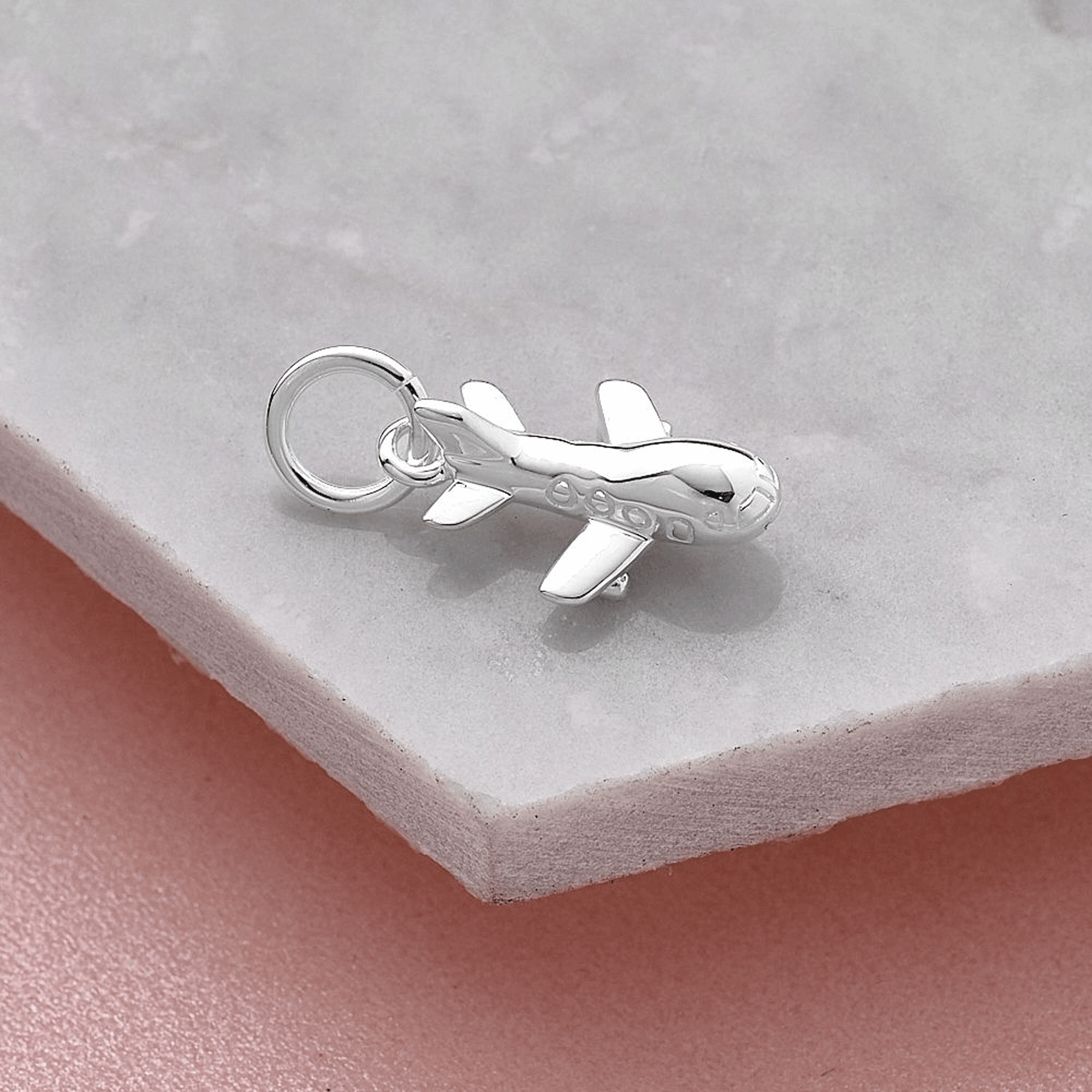 Silver airplane charm on a light gray surface