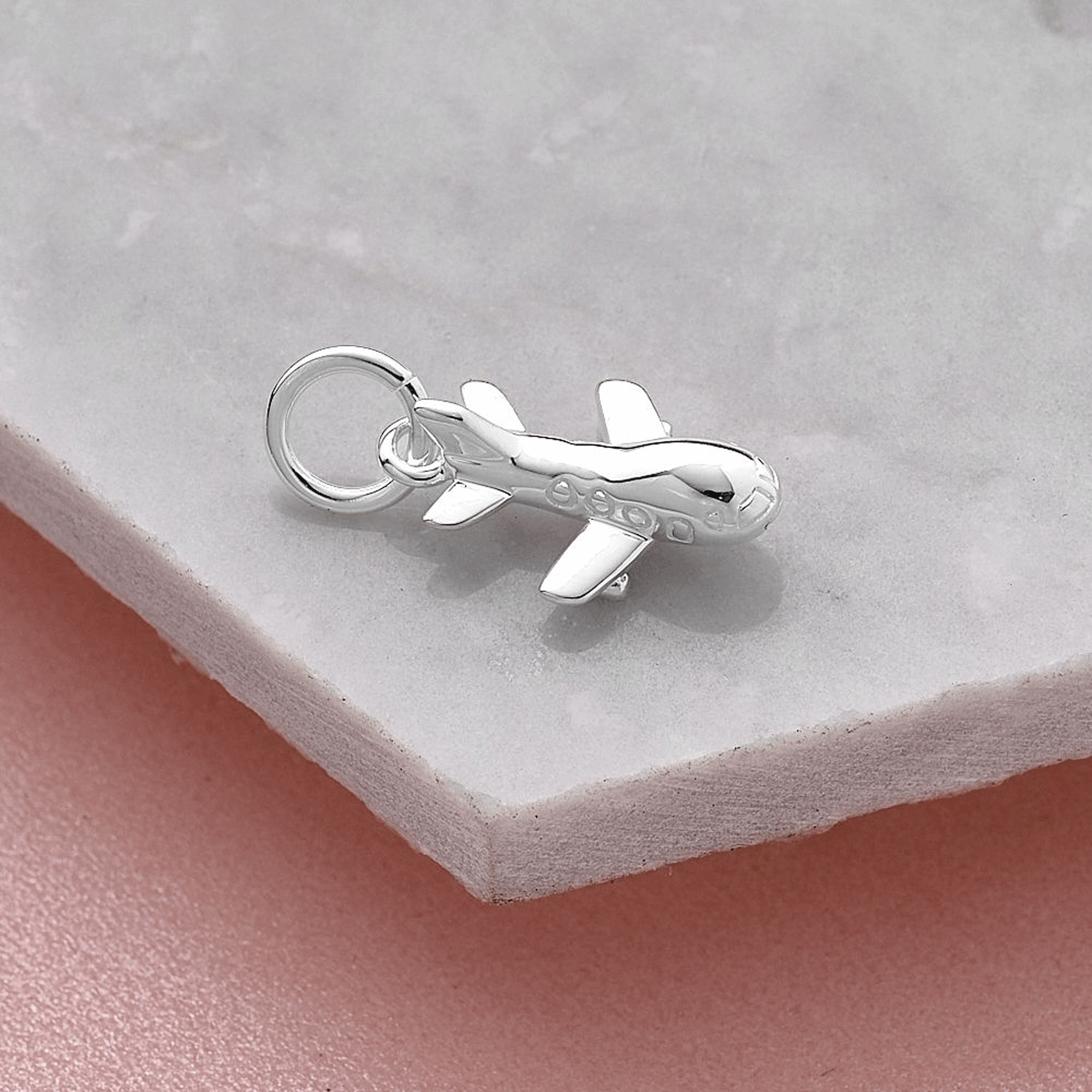 Silver airplane charm on a light gray surface