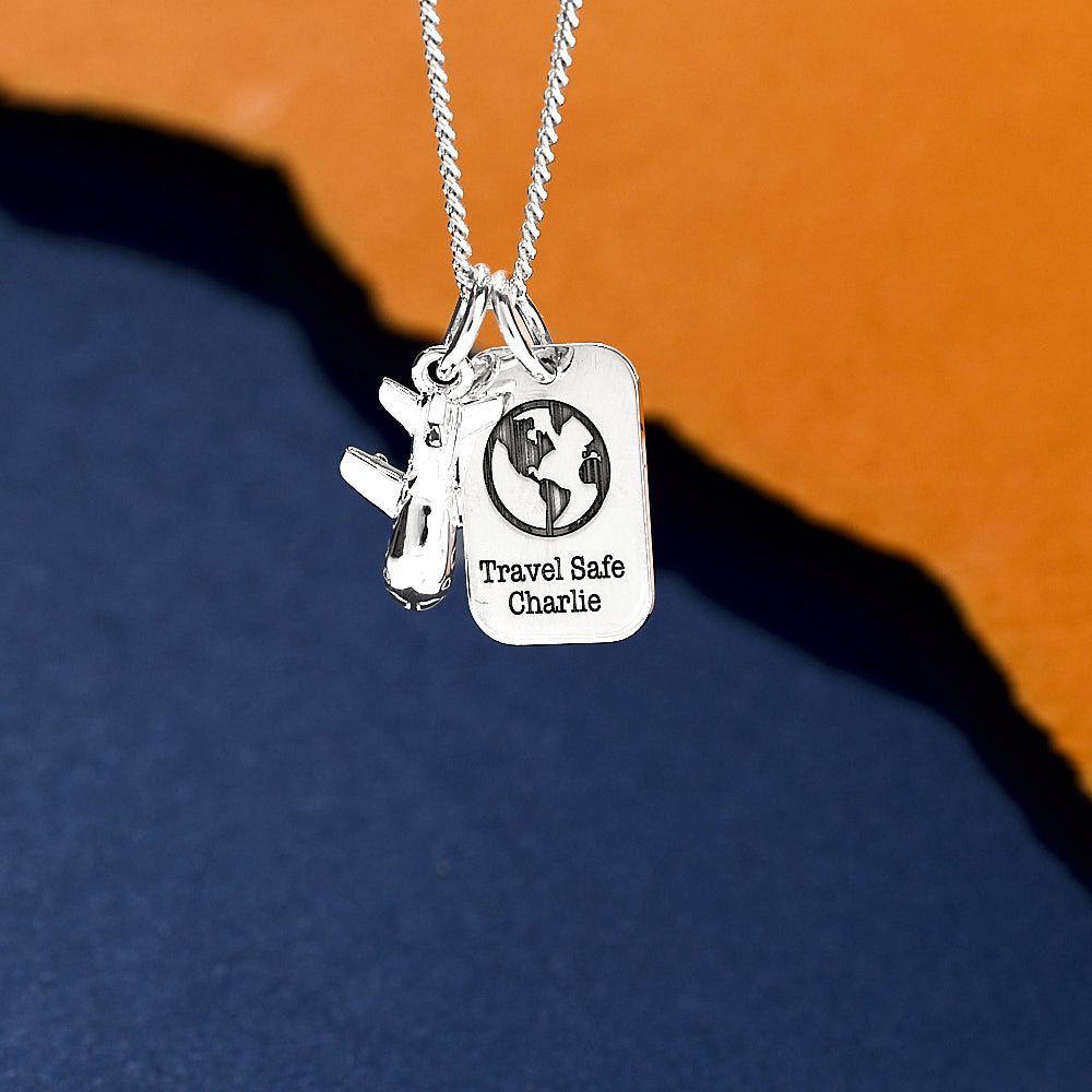 Silver necklace with two tags, one featuring an aeroplane and the other 'Travel Safe Charlie', dog tag
