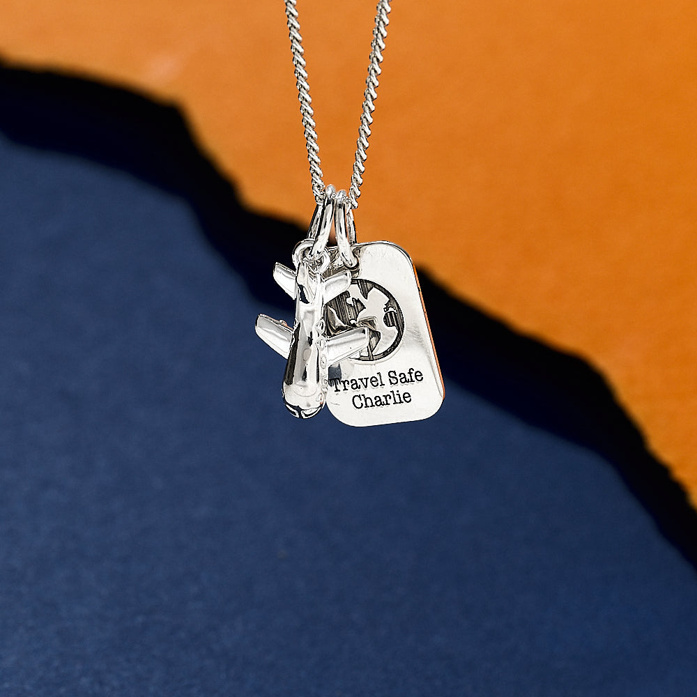 Silver necklace with two tags, one featuring an aeroplane and the other 'Travel Safe Charlie', dog tag