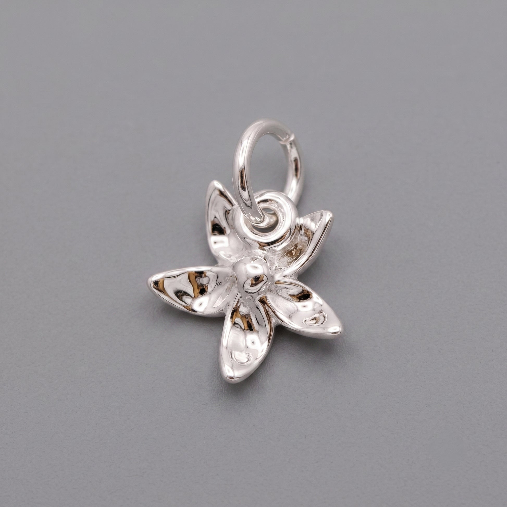 Silver flower-shaped pendant on a gray background