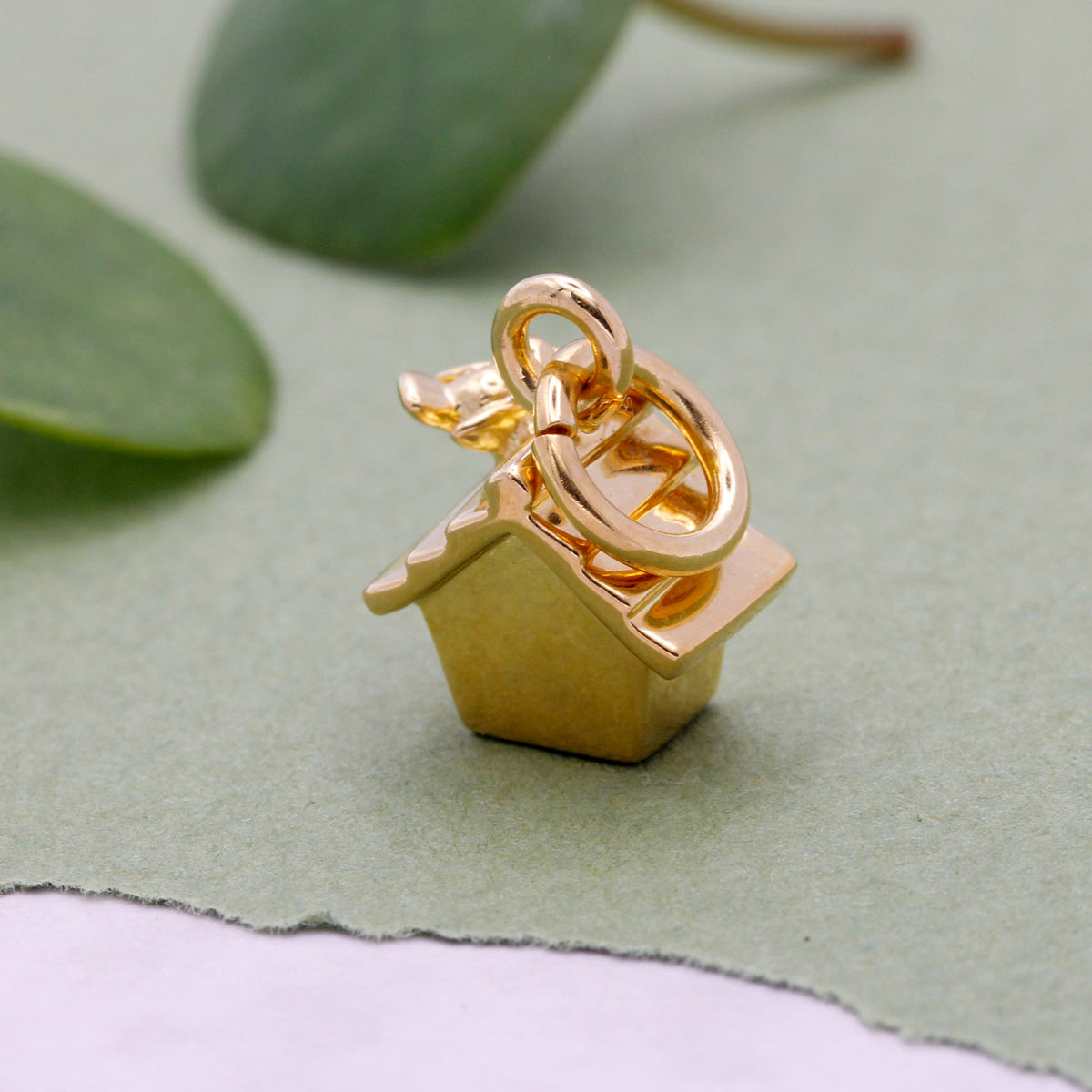 Close-up of gold plated bird house charm showing intricate details and craftsmanship