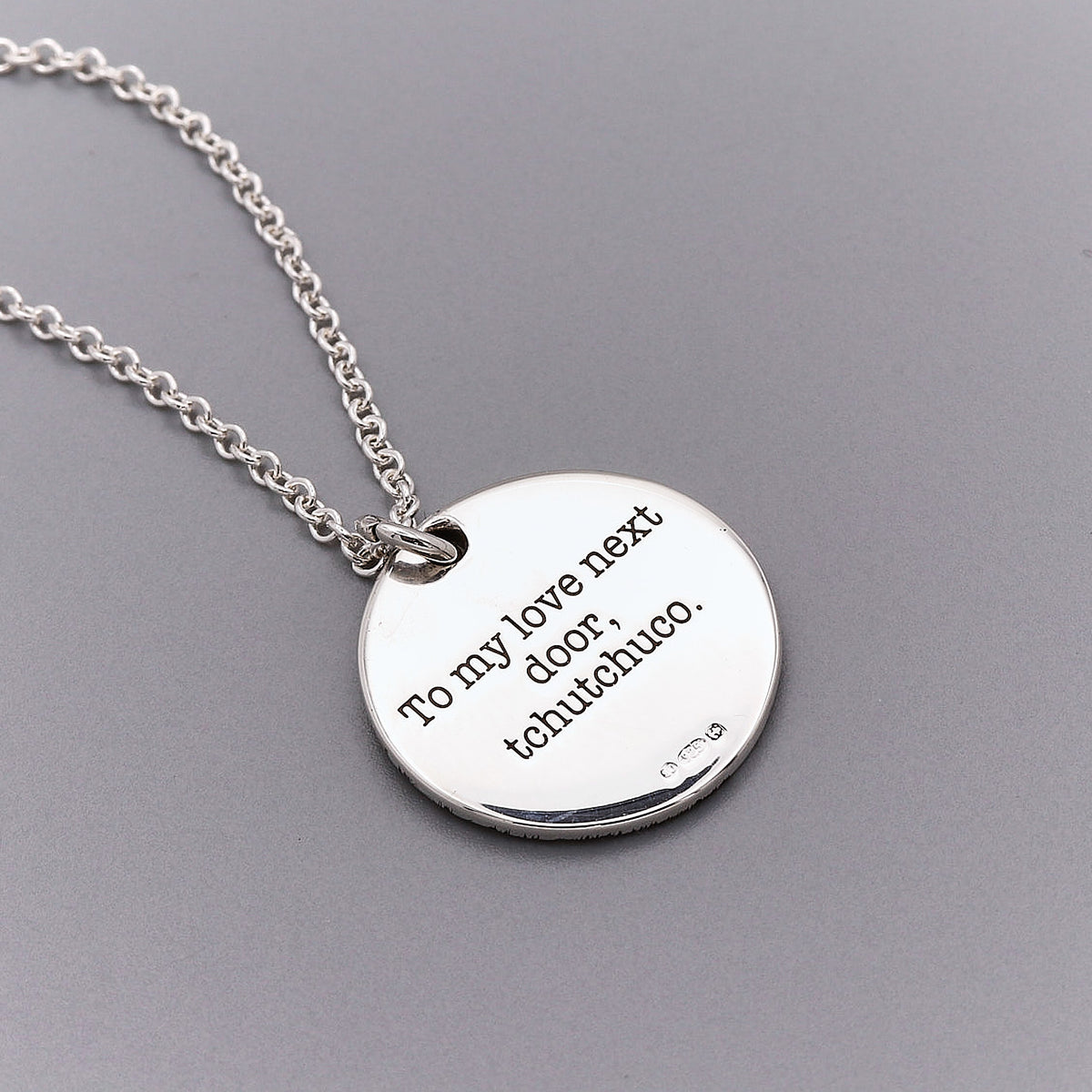 Silver necklace with a round pendant on a gray background