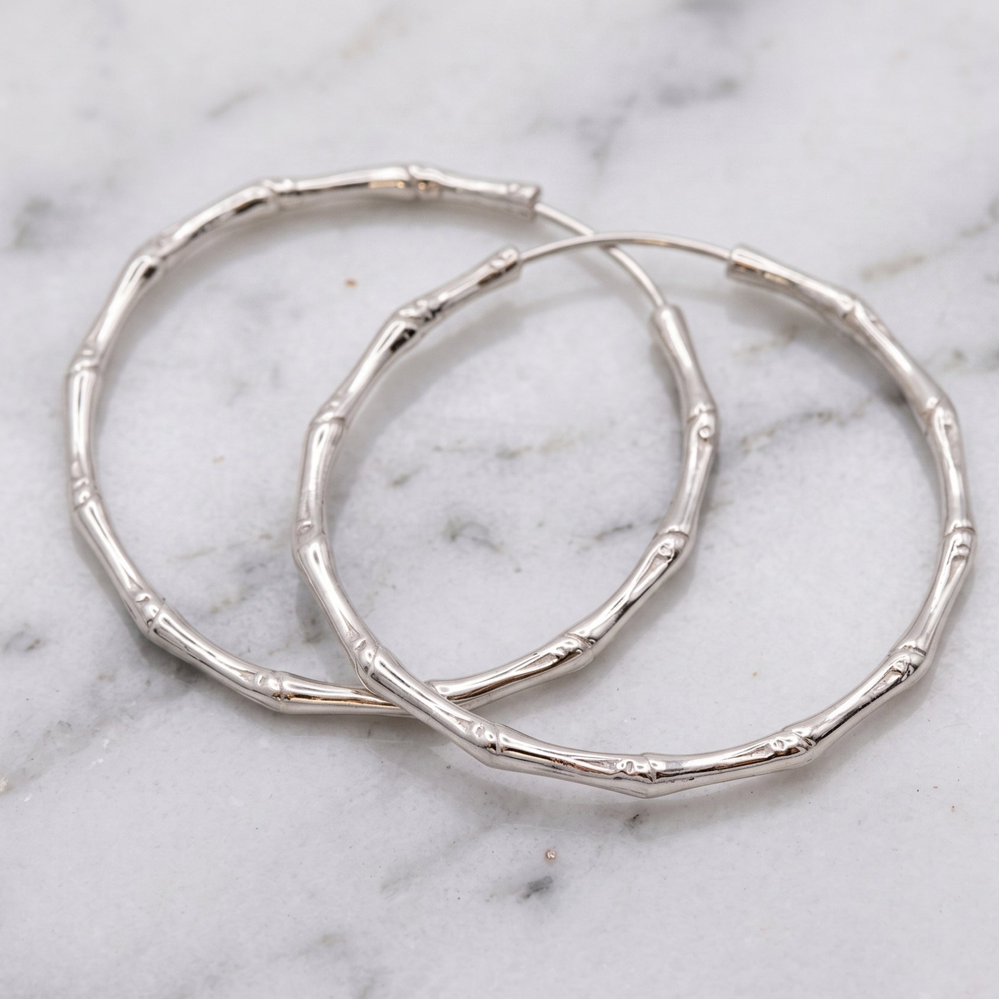 Silver hoop earrings on a marble surface