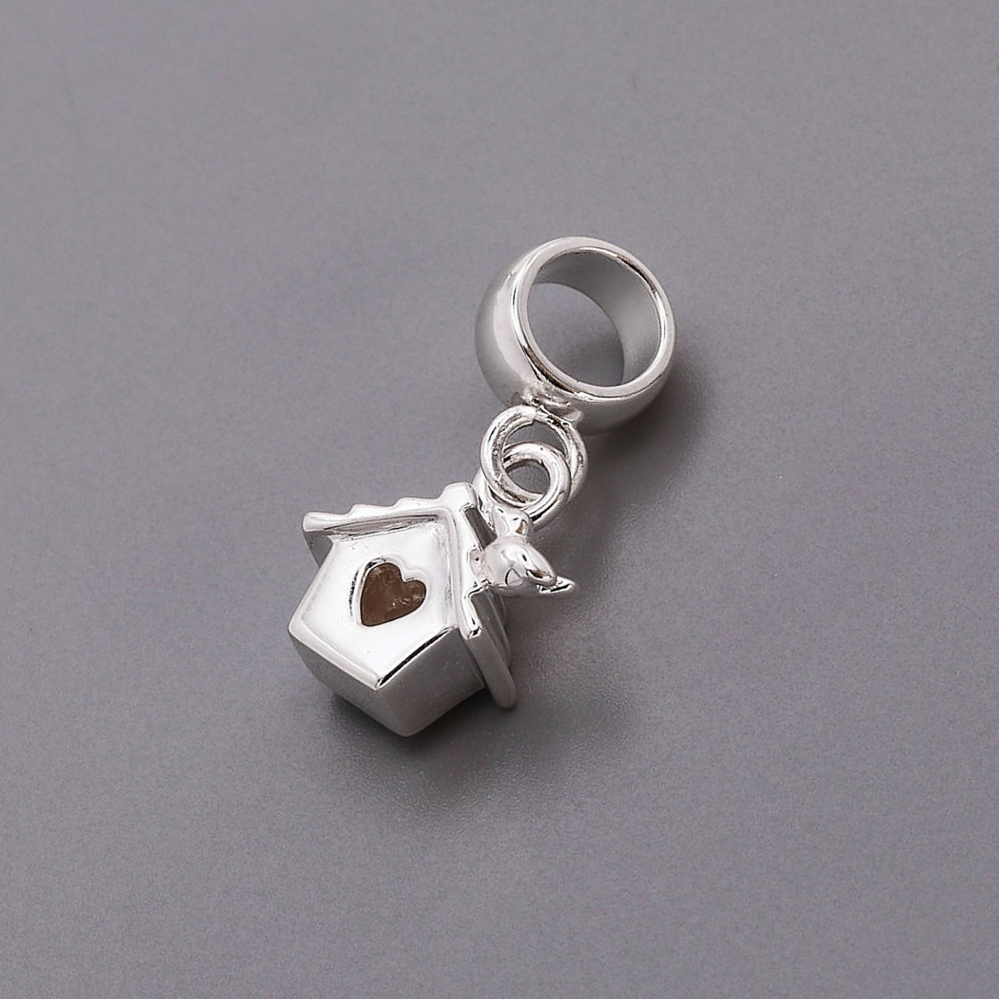 Silver charm with a birdhouse and heart on a gray background