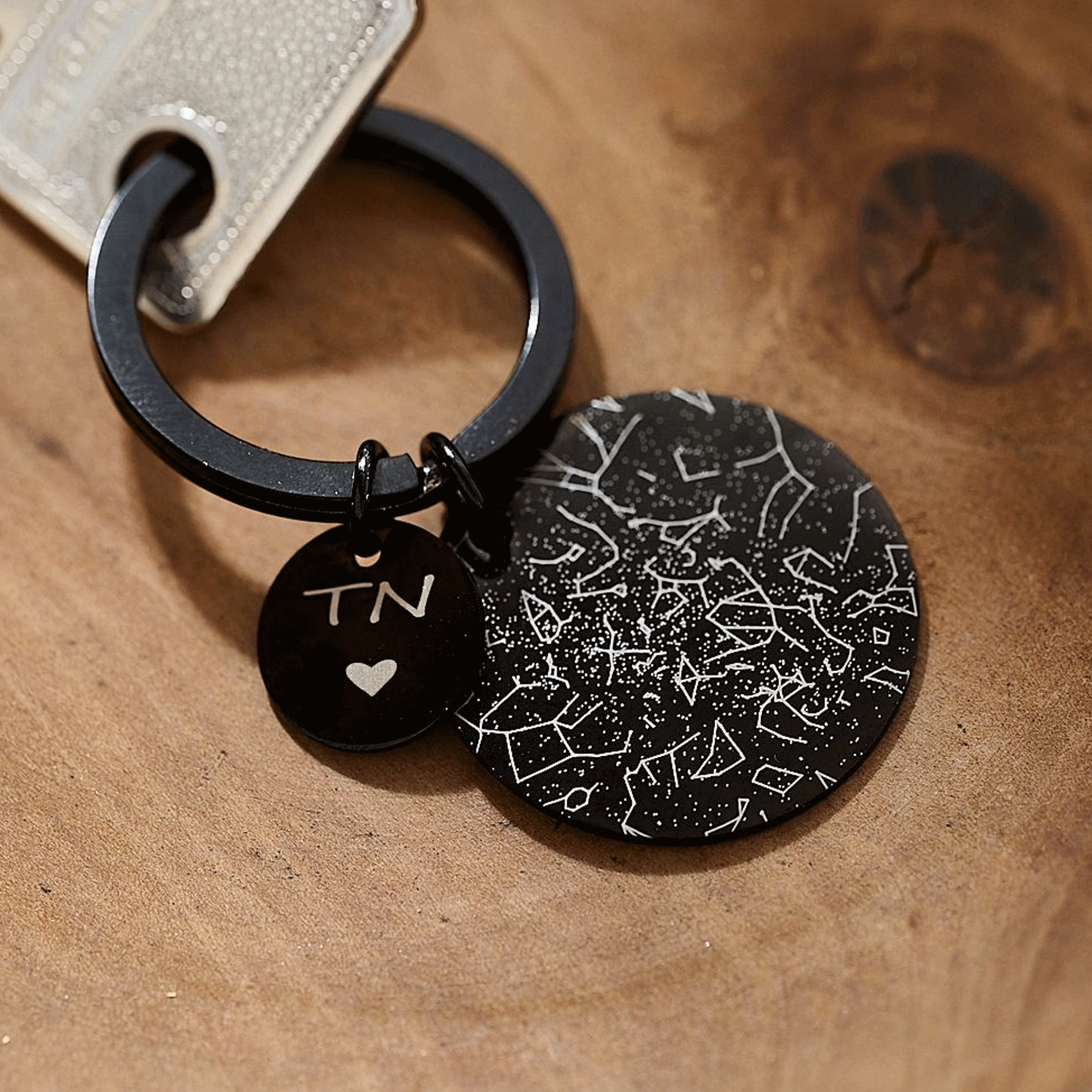 Black keychain with personalised star constellation design on a wooden surface