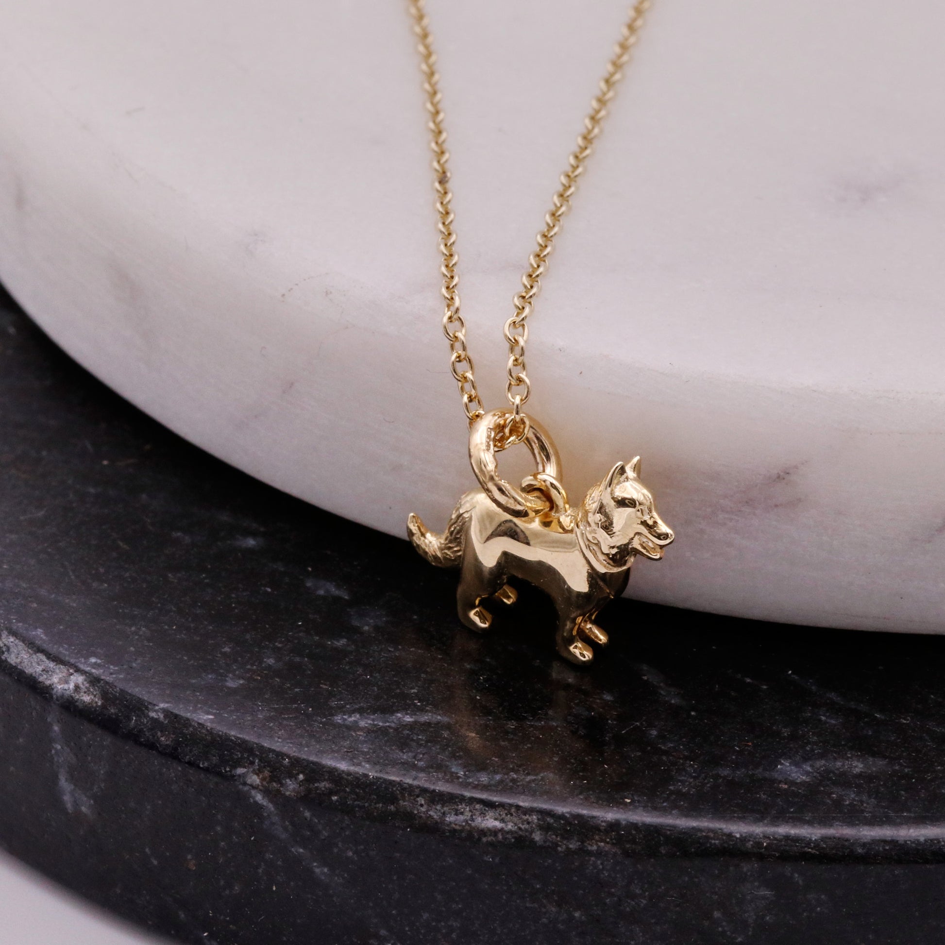 Gold dog-shaped pendant necklace on a marble surface