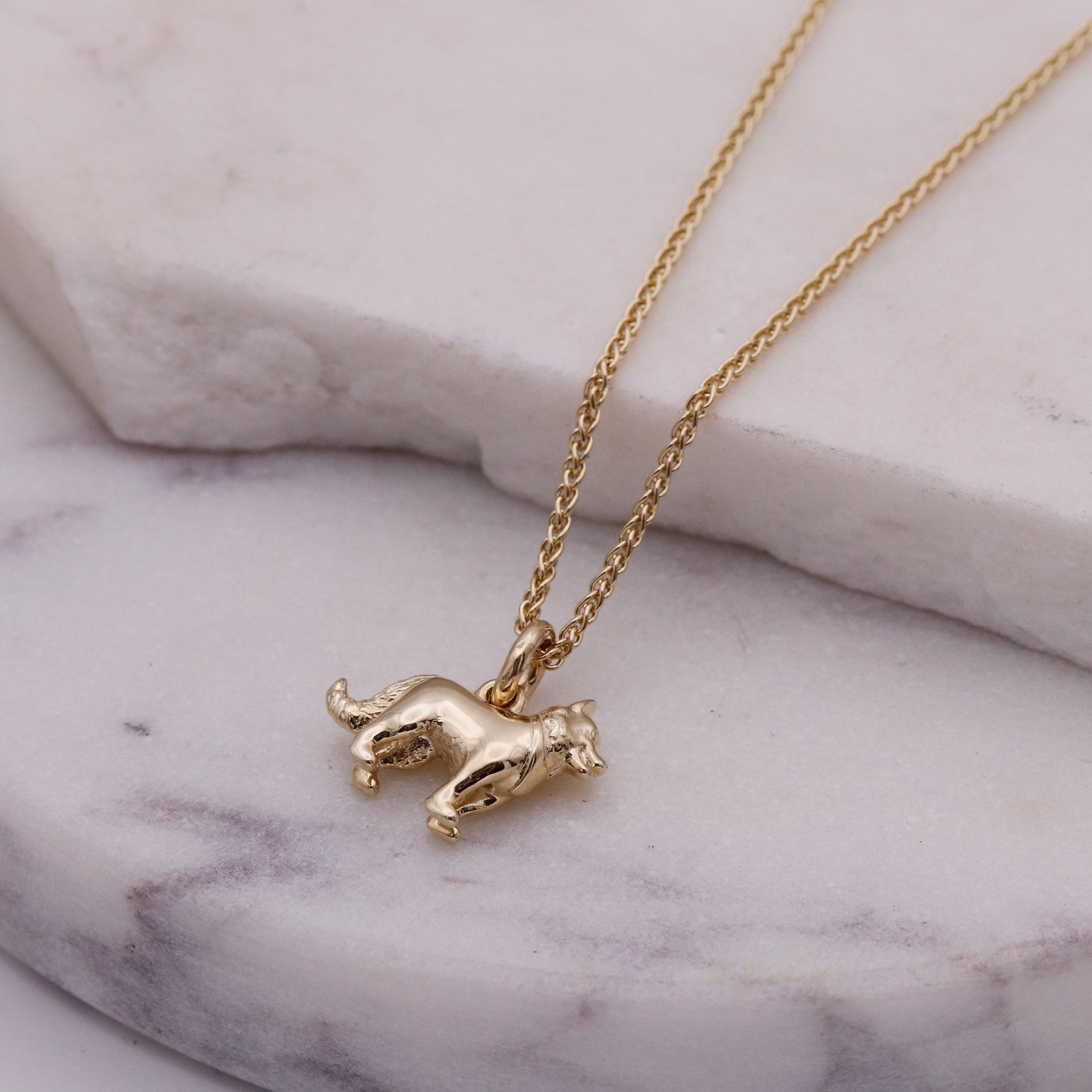 Gold border collie necklace with a small pendant on a marble surface