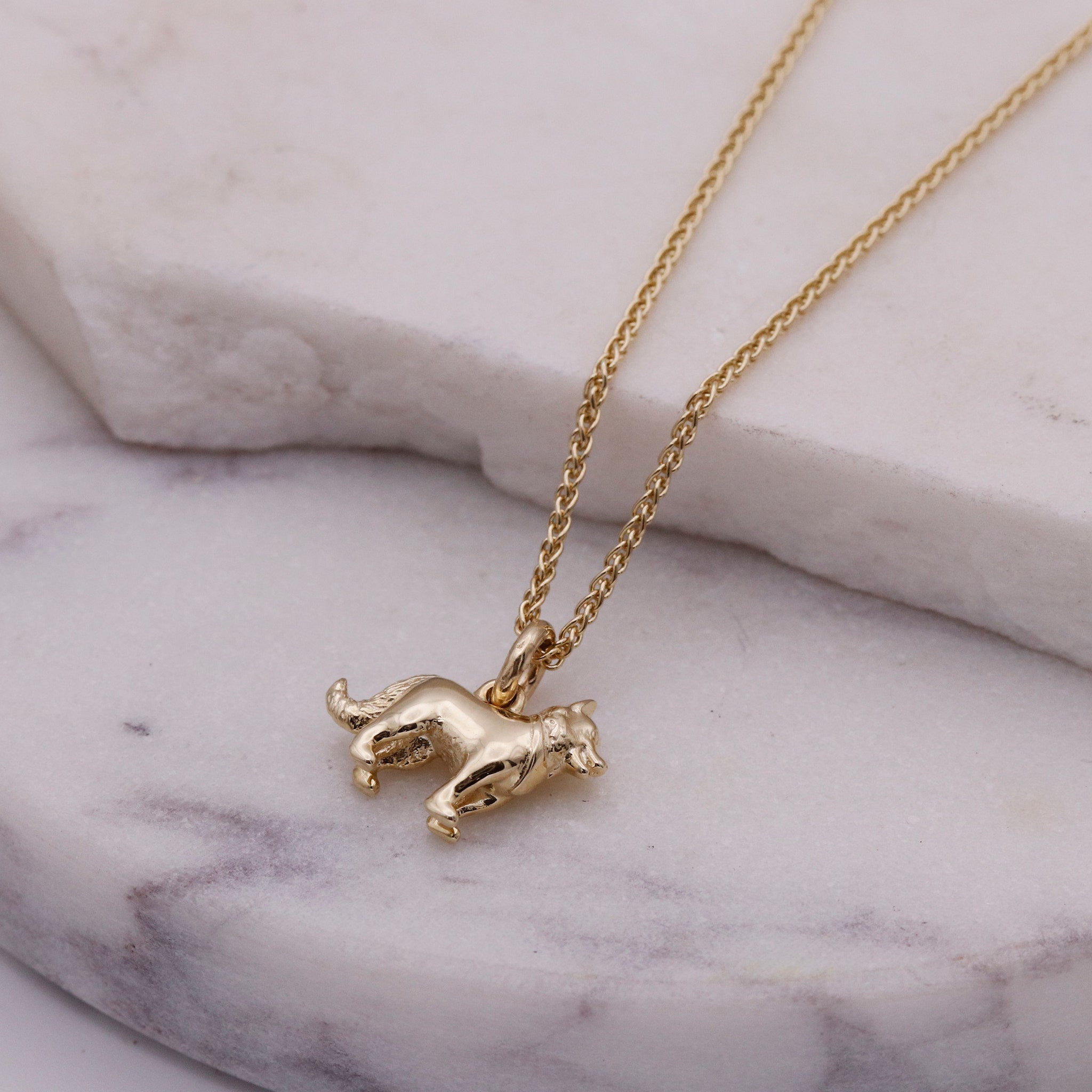 Gold border collie necklace with a small pendant on a marble surface