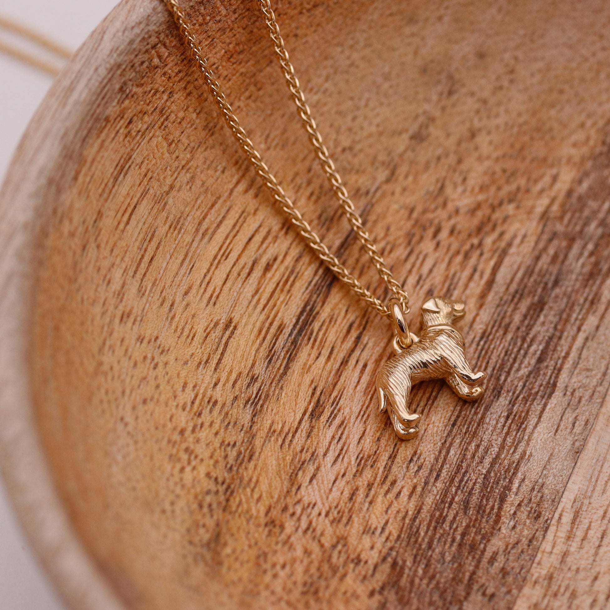 Gold dog-shaped pendant necklace on a wooden surface
