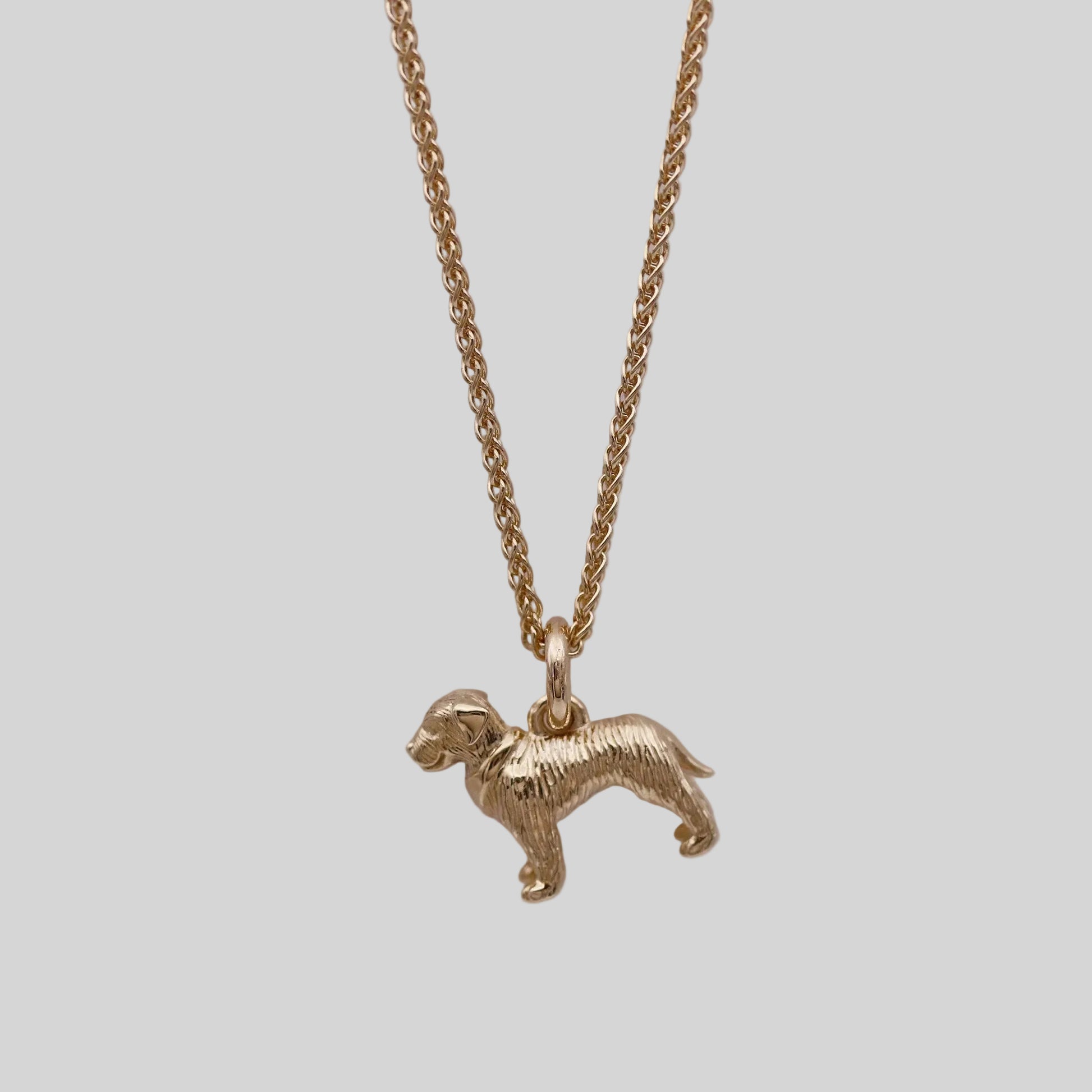 Gold dog-shaped pendant on a chain against a gray background