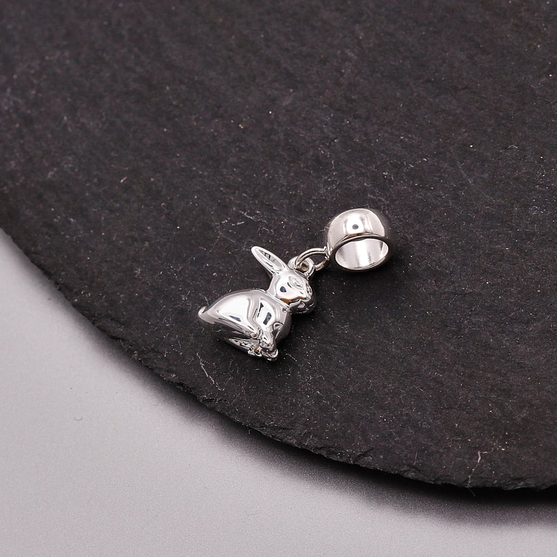 Silver rabbit charm on a dark stone surface