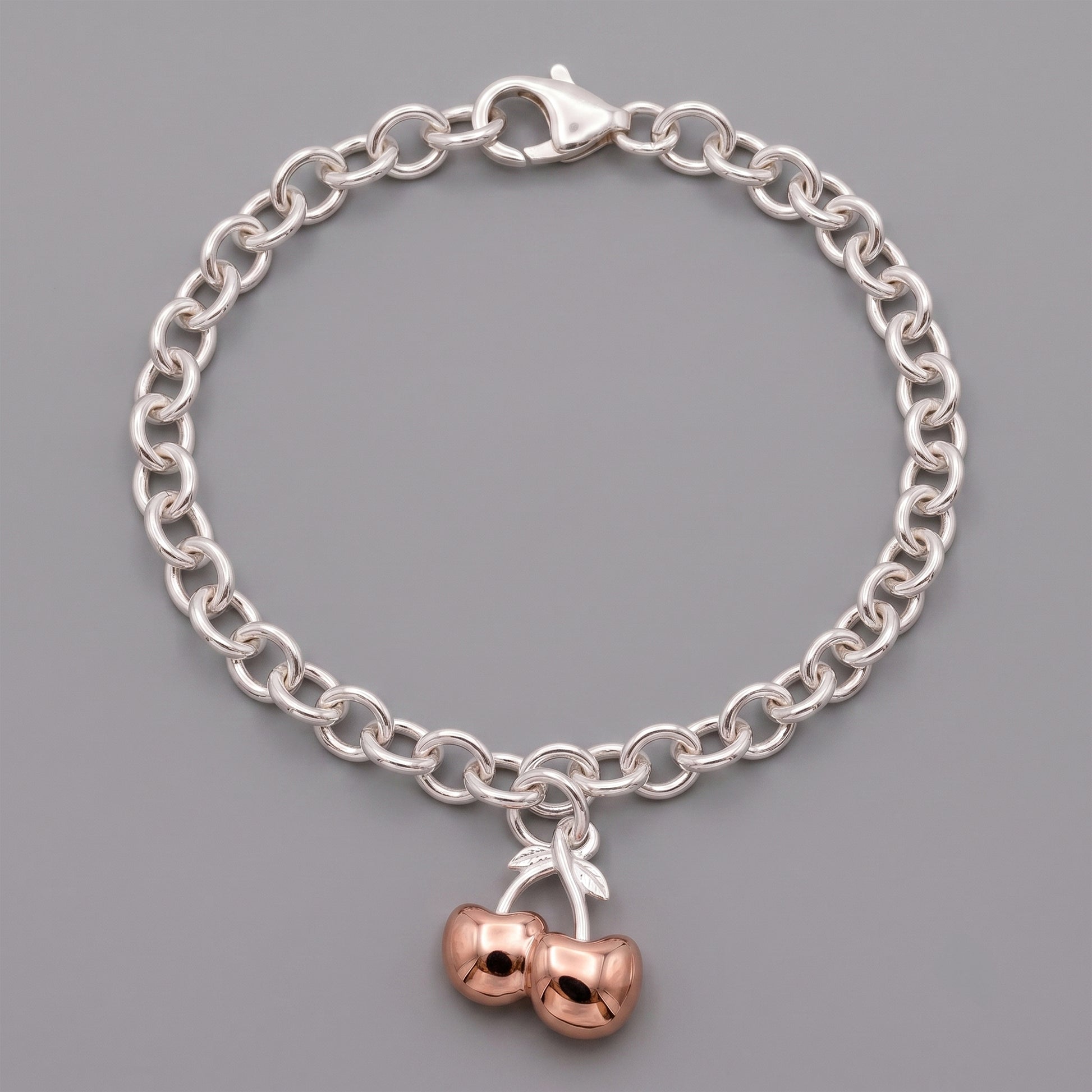 Silver chain bracelet with a cherry charm on a gray background