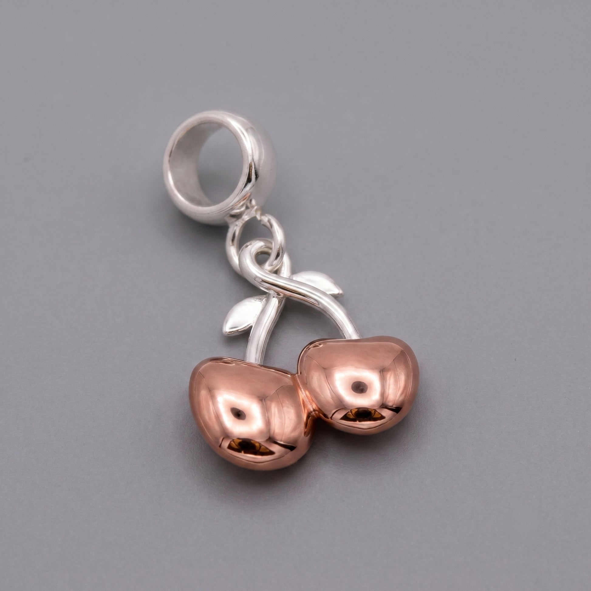 Silver and rose gold charm on a gray background