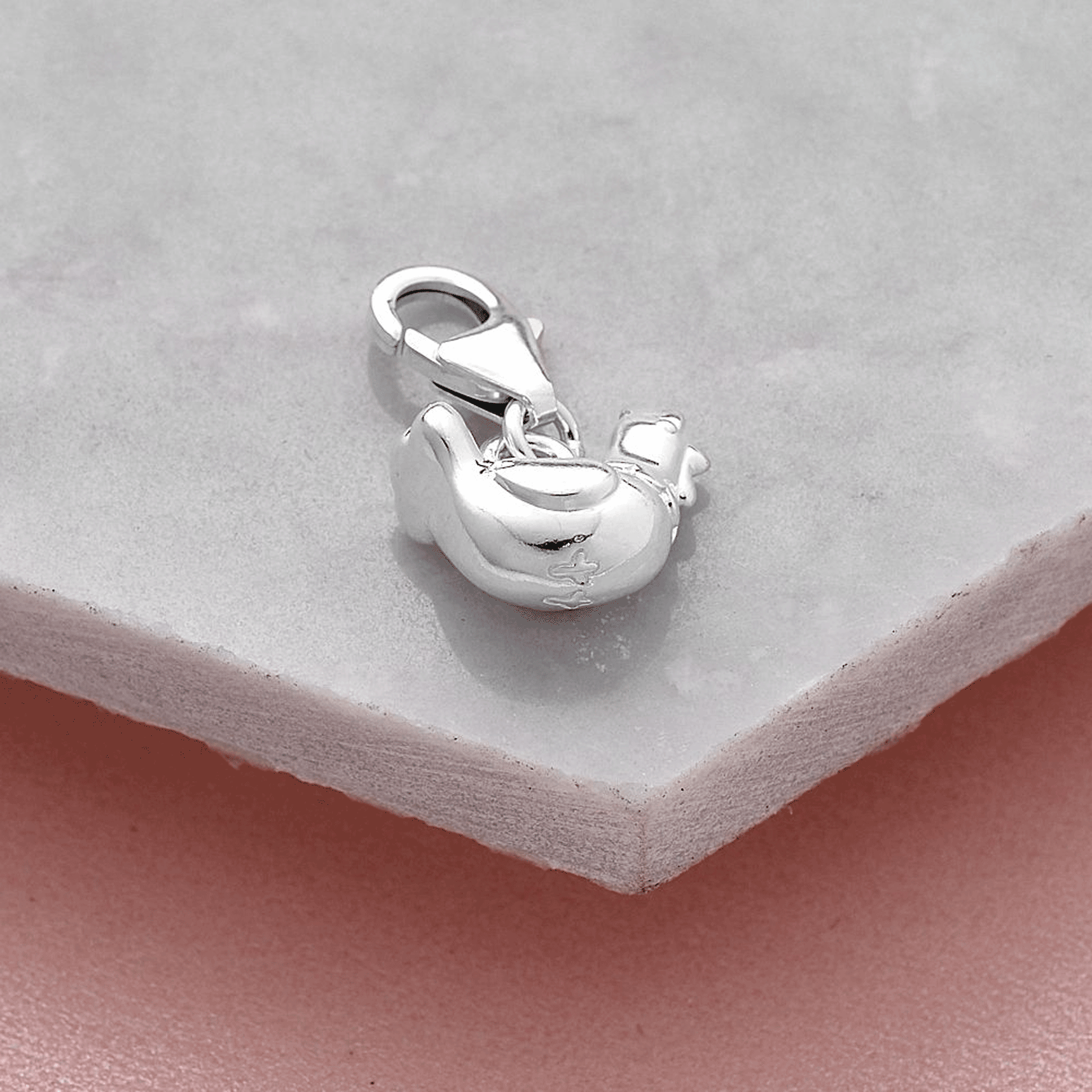 Silver chicken charm with feet detail on a light gray background