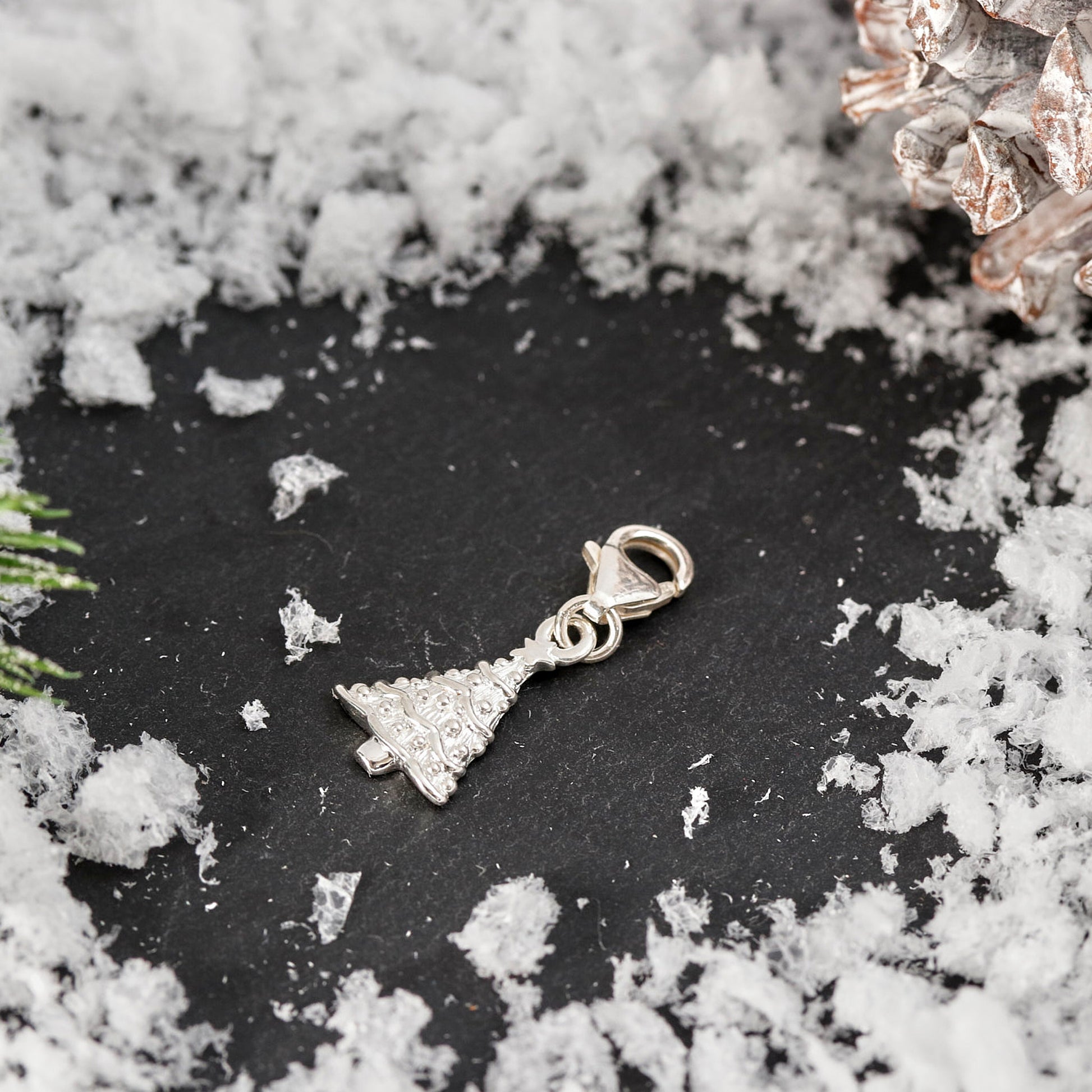 Silver bell-shaped charm on a dark surface with snow-like texture