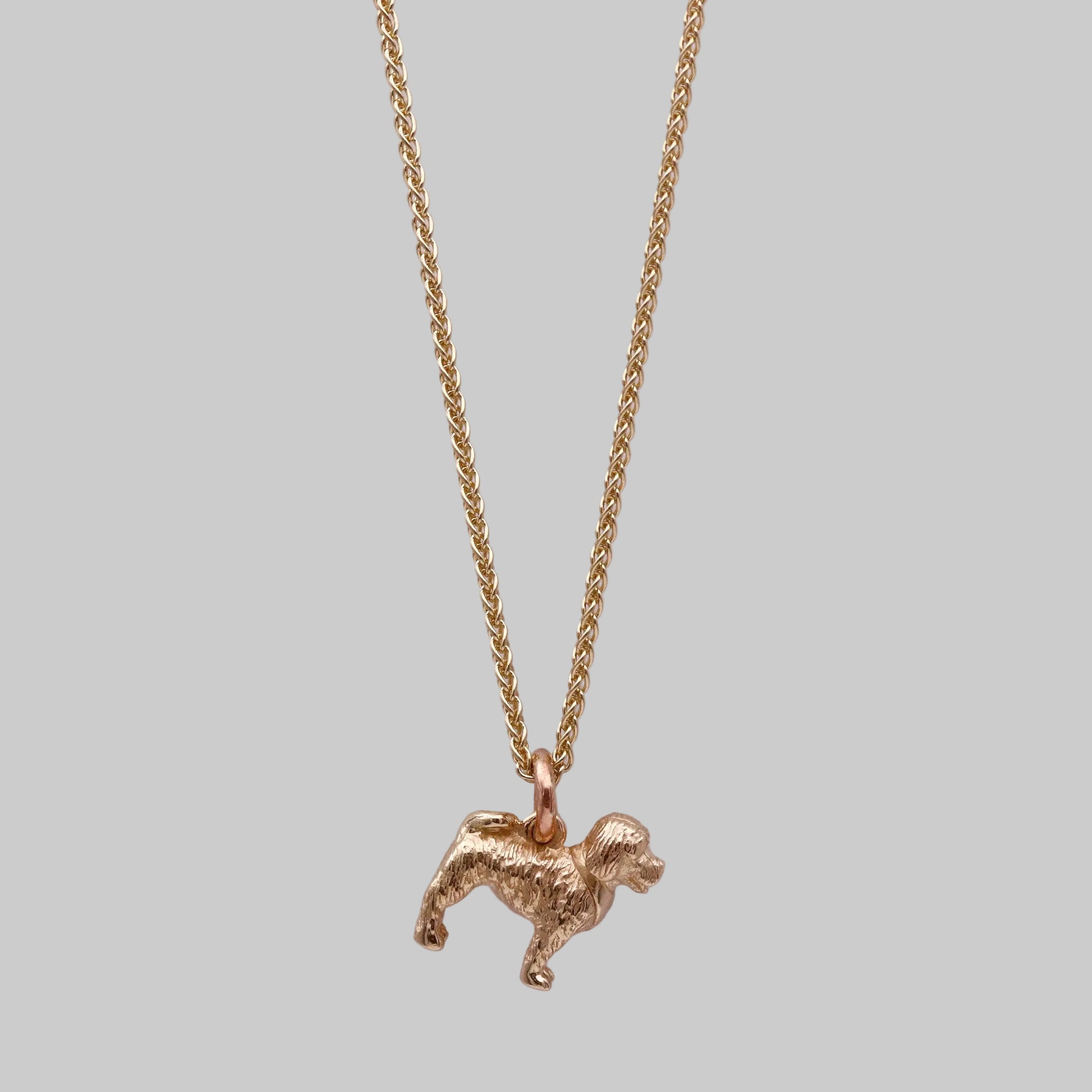 Gold dog-shaped pendant on a chain against a white background