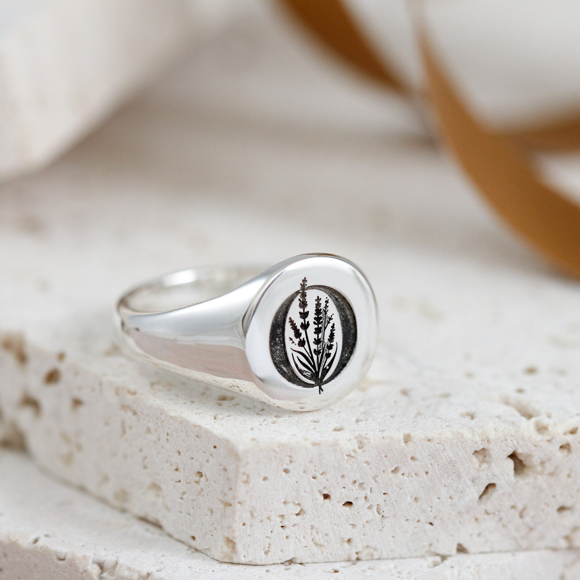 Silver ring with a leaf design on a textured surface