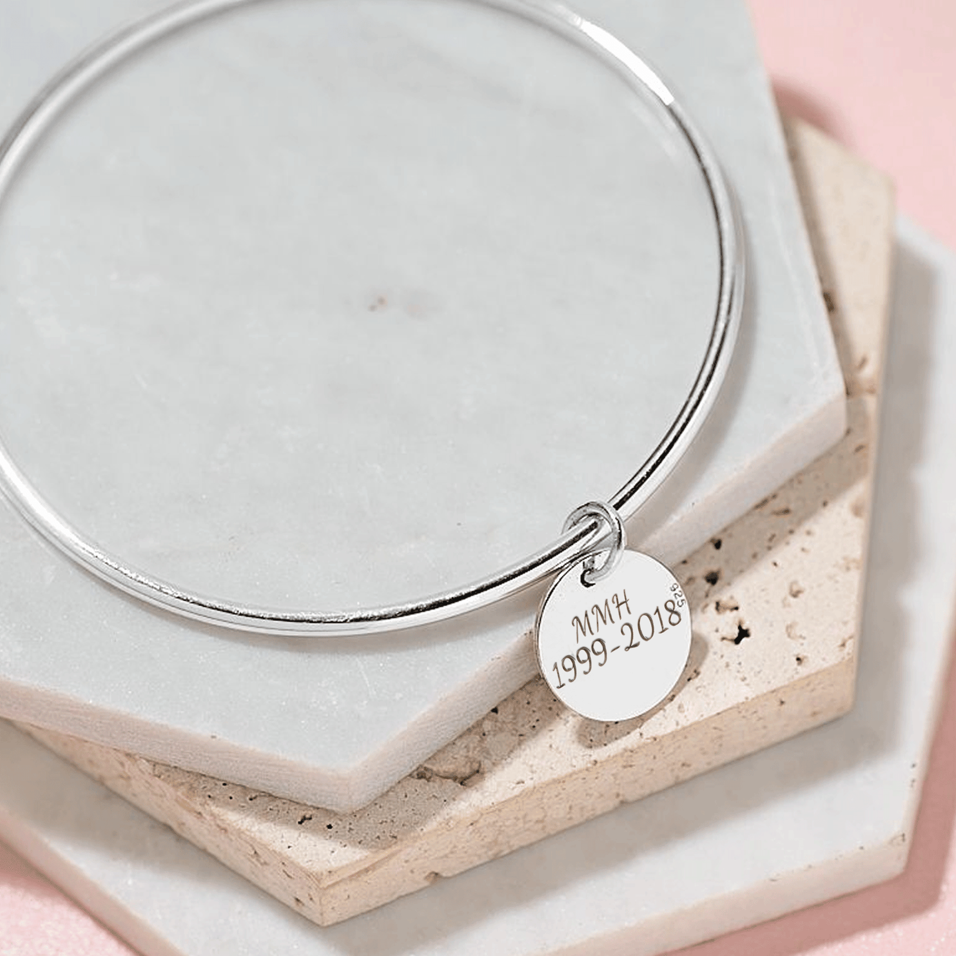 Silver bangle with a engraved charm on a light background
