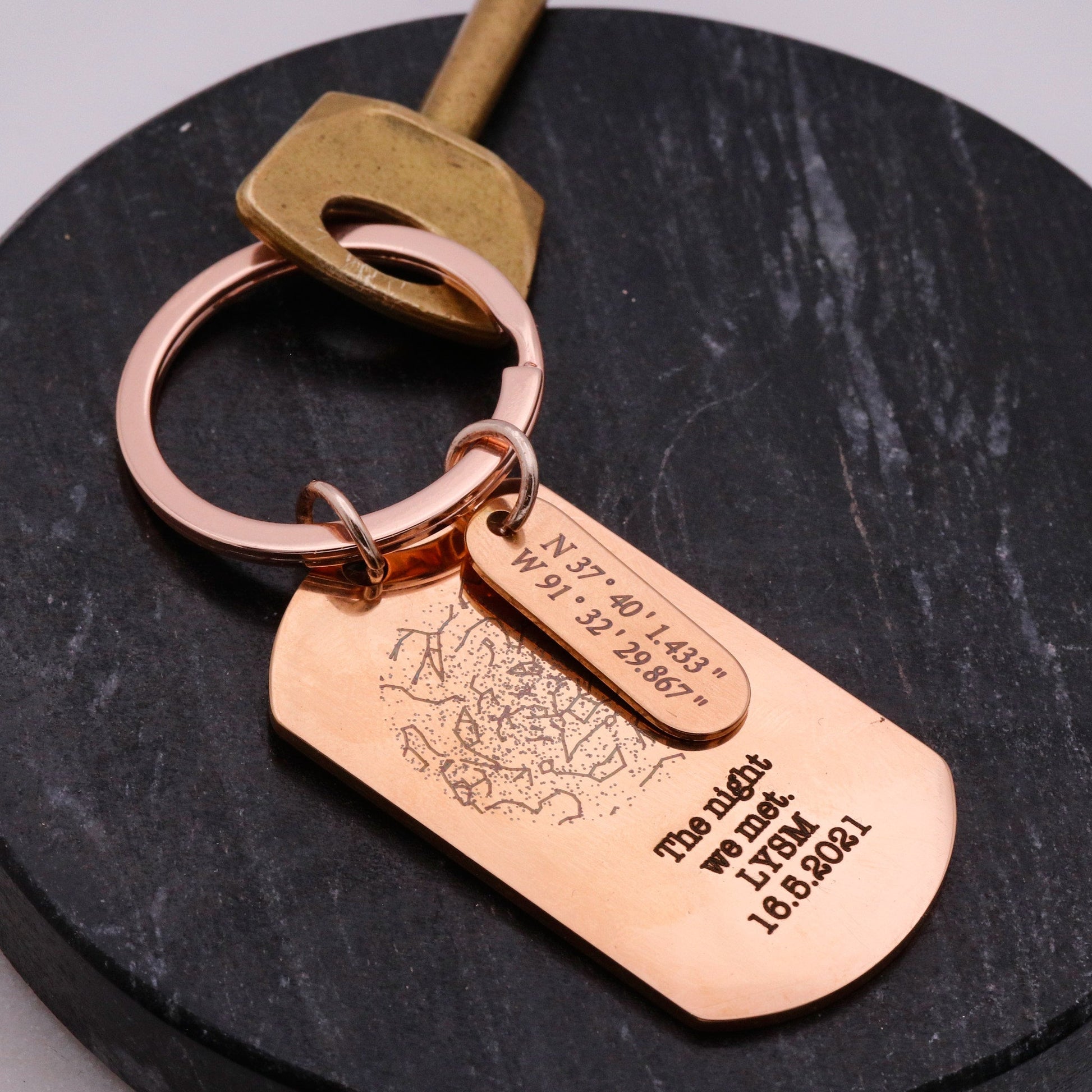 Rose gold keychain with engraved tag on a dark surface
